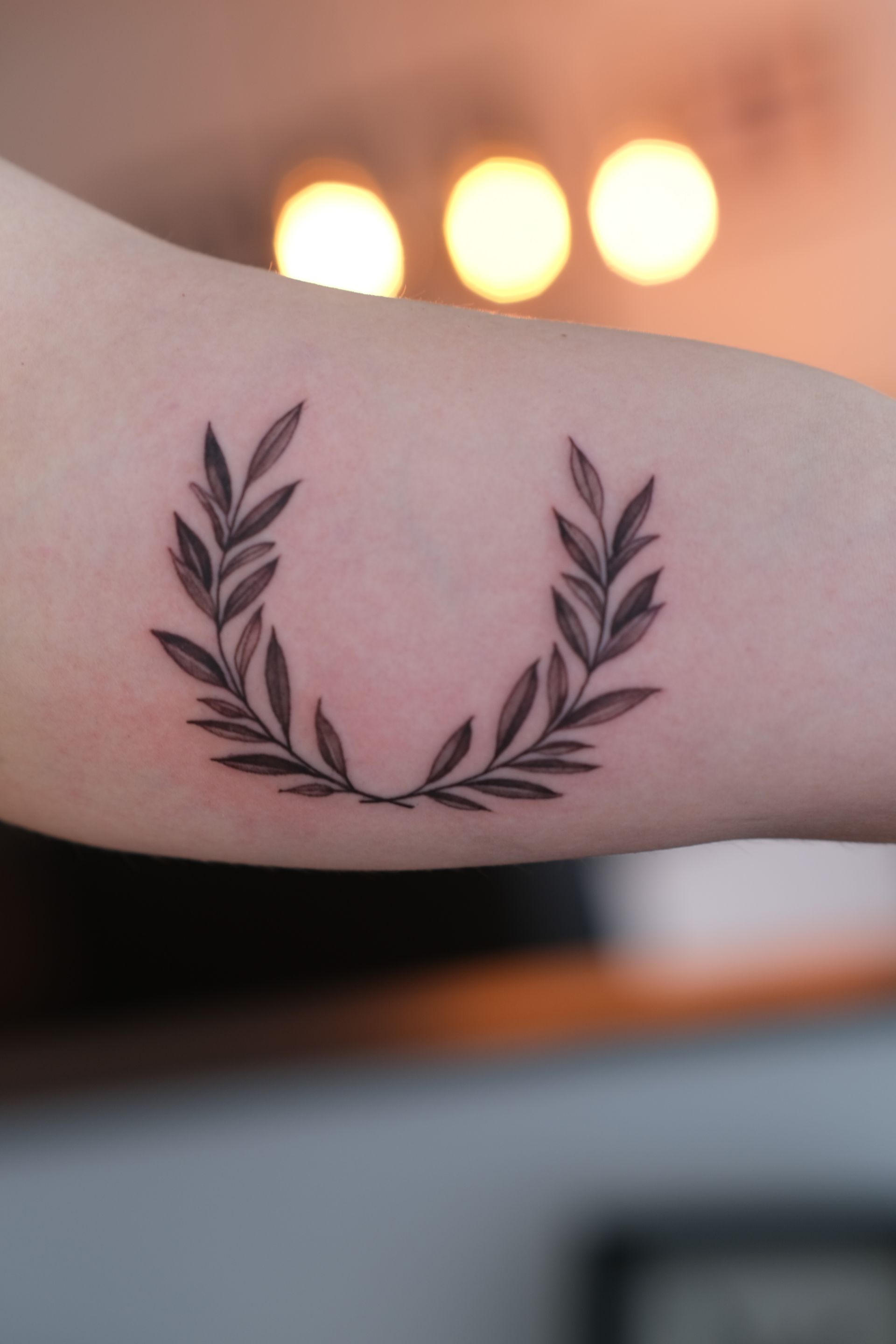 Eine Tätowierung eines Lorbeerkranzes auf dem Arm einer Person