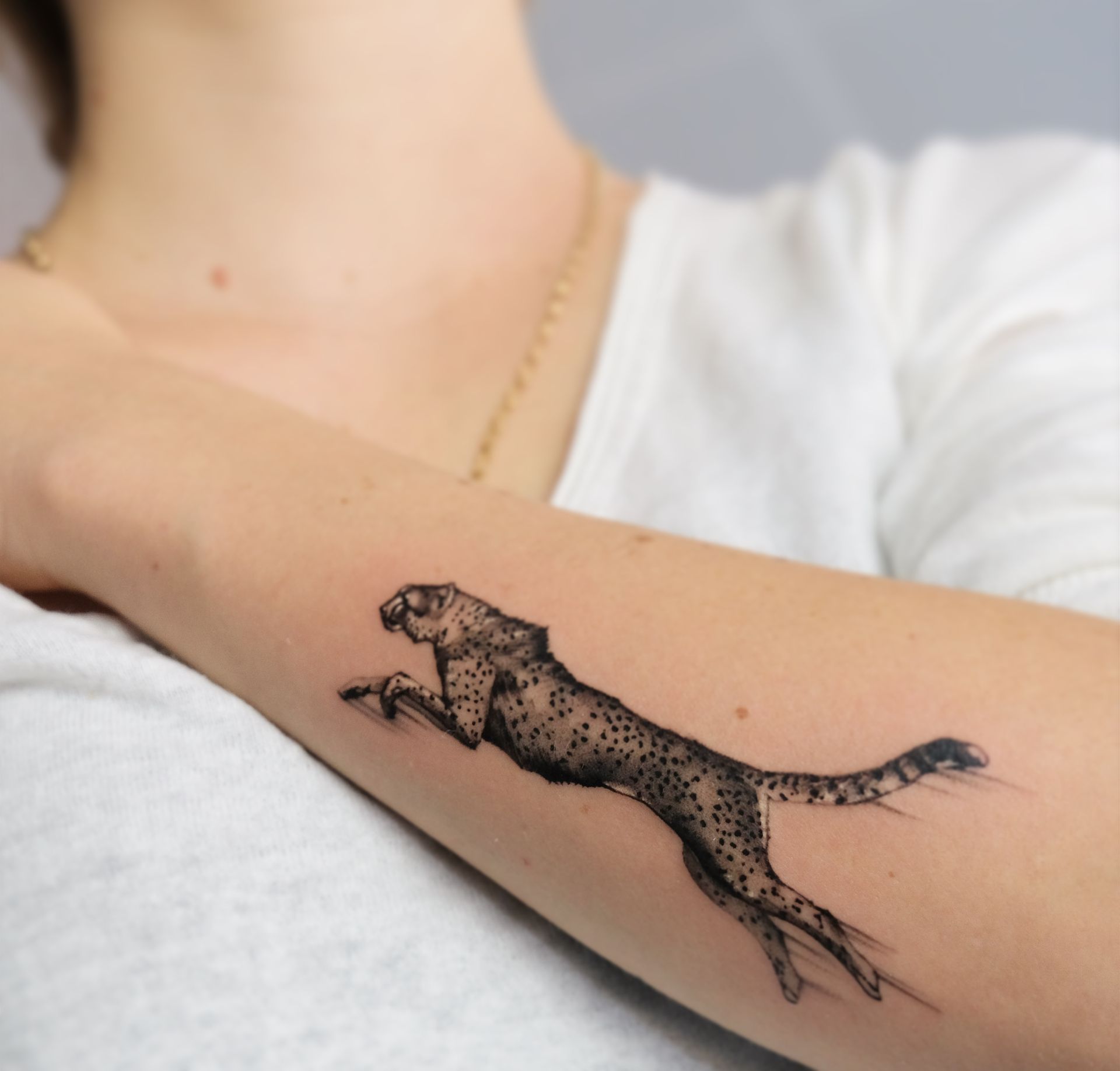 Eine Frau hat ein Tattoo eines Geparden auf ihrem Arm