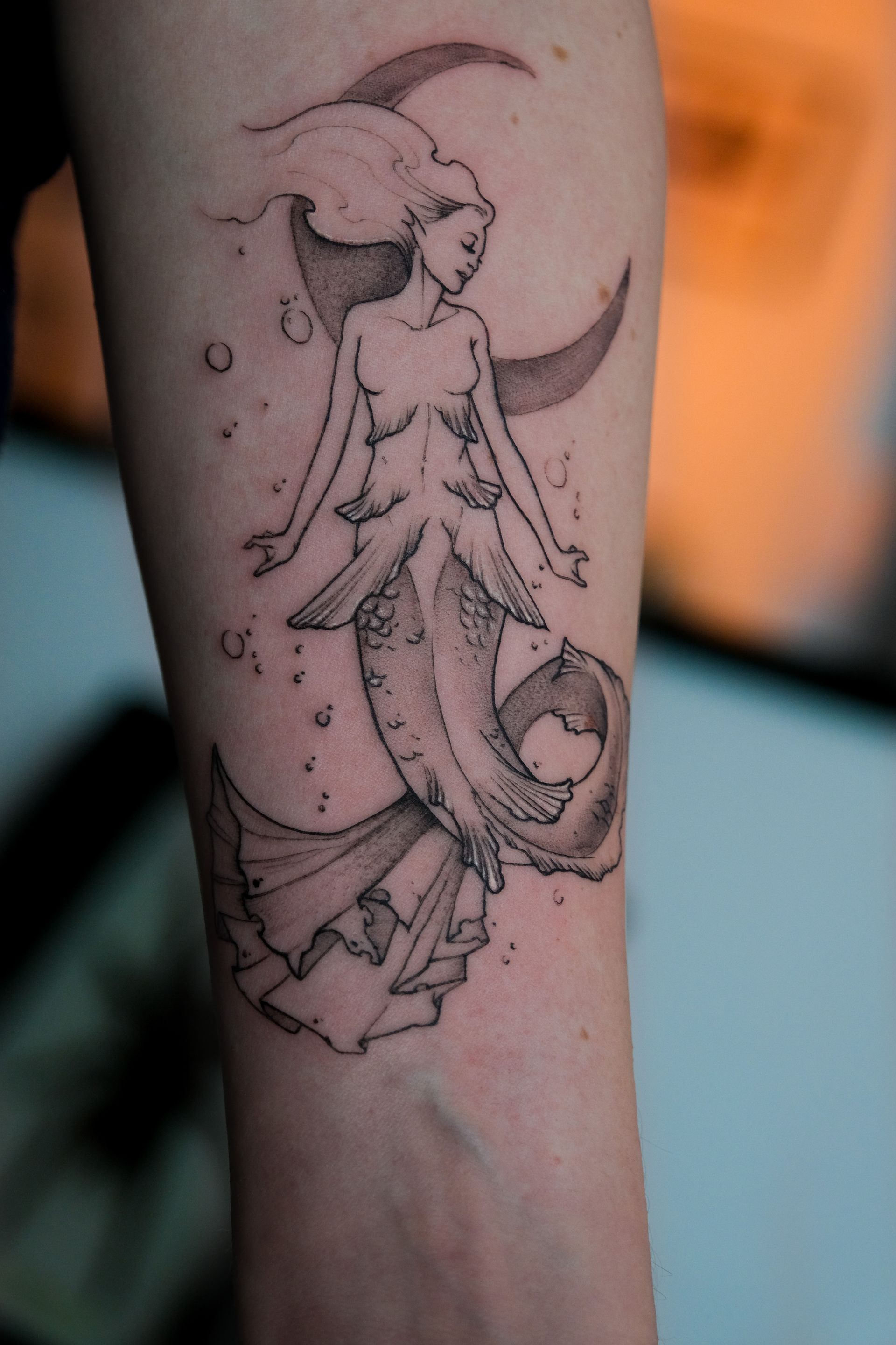 Ein Tattoo einer Meerjungfrau auf dem Arm einer Person