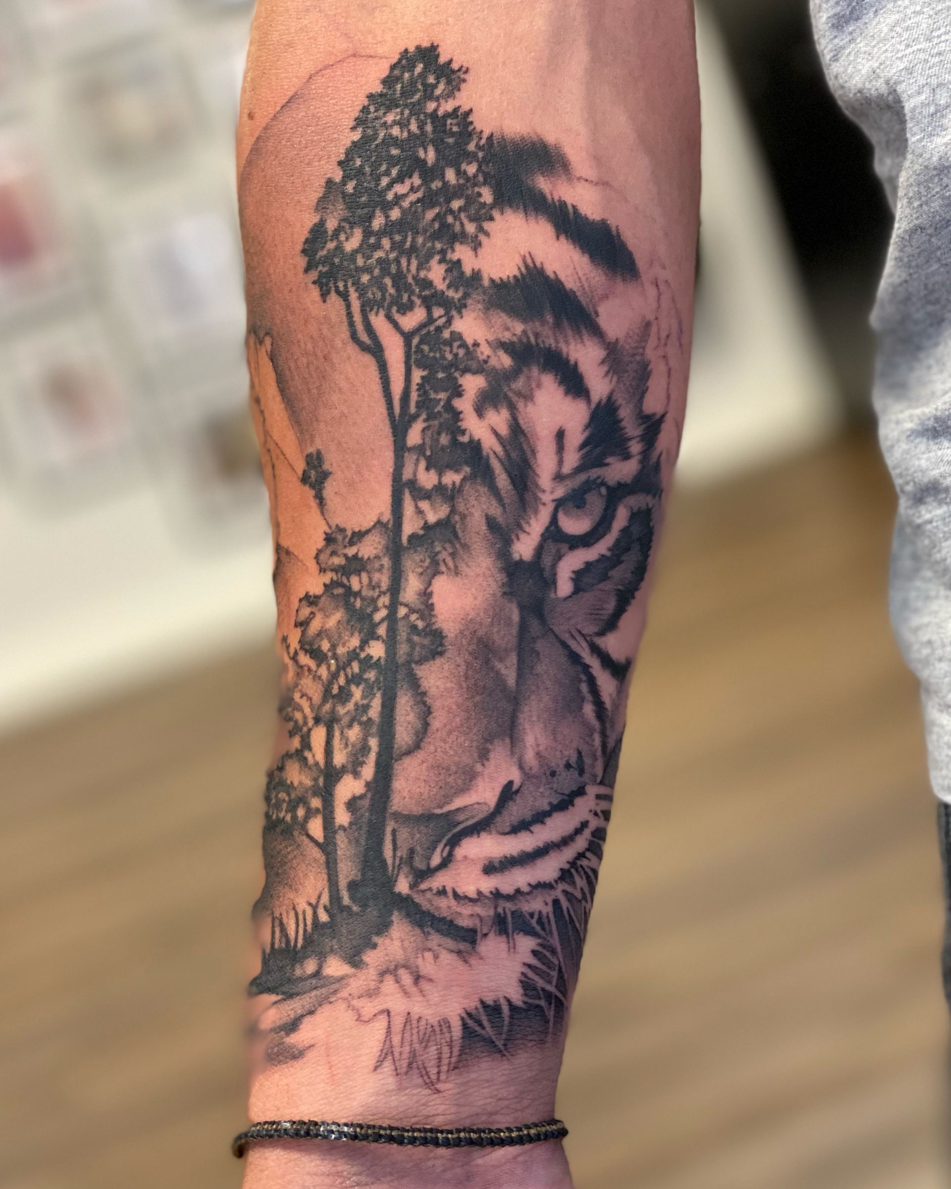 Ein Mann hat ein Tattoo von einem Tiger und Bäumen auf seinem Arm