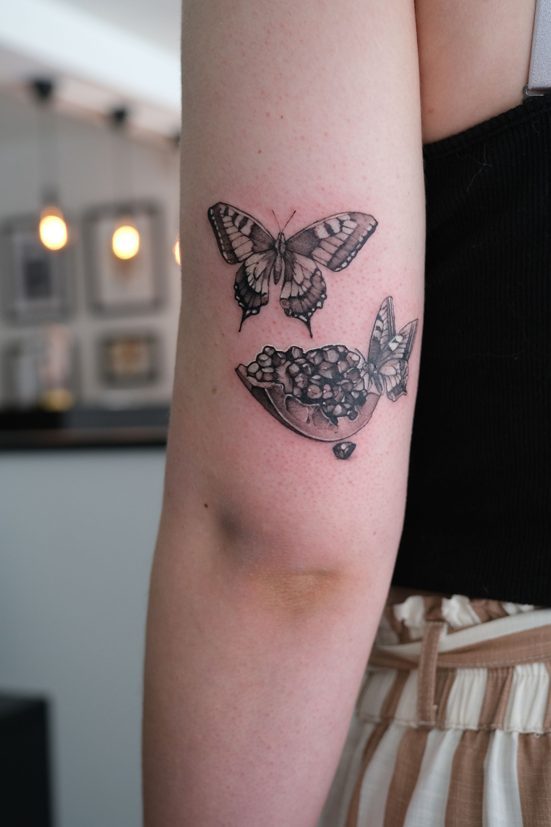 Eine Frau hat ein Tattoo von zwei Schmetterlingen auf ihrem Arm
