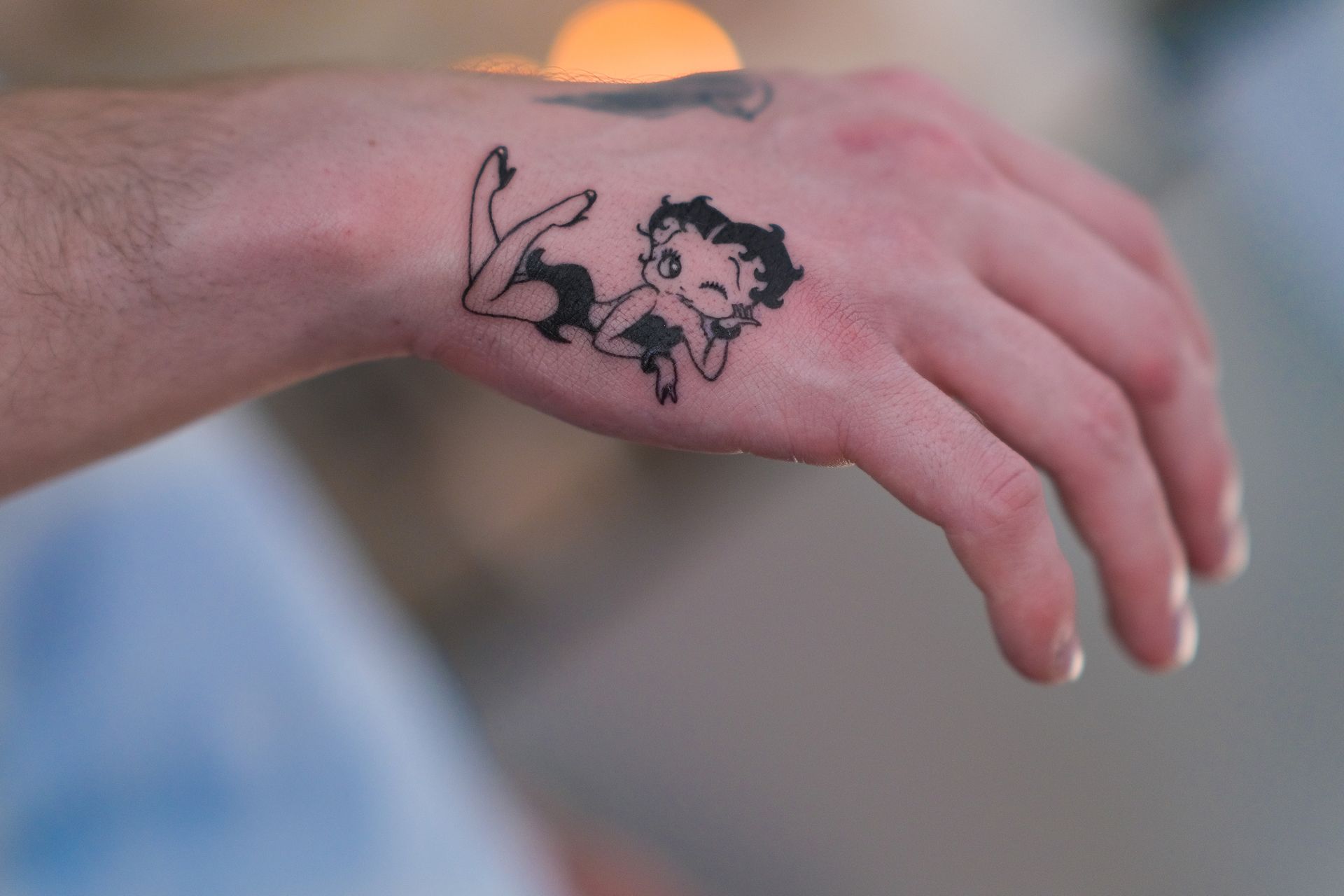 Eine Person hat ein Betty-Boop-Tattoo auf ihrem Handgelenk