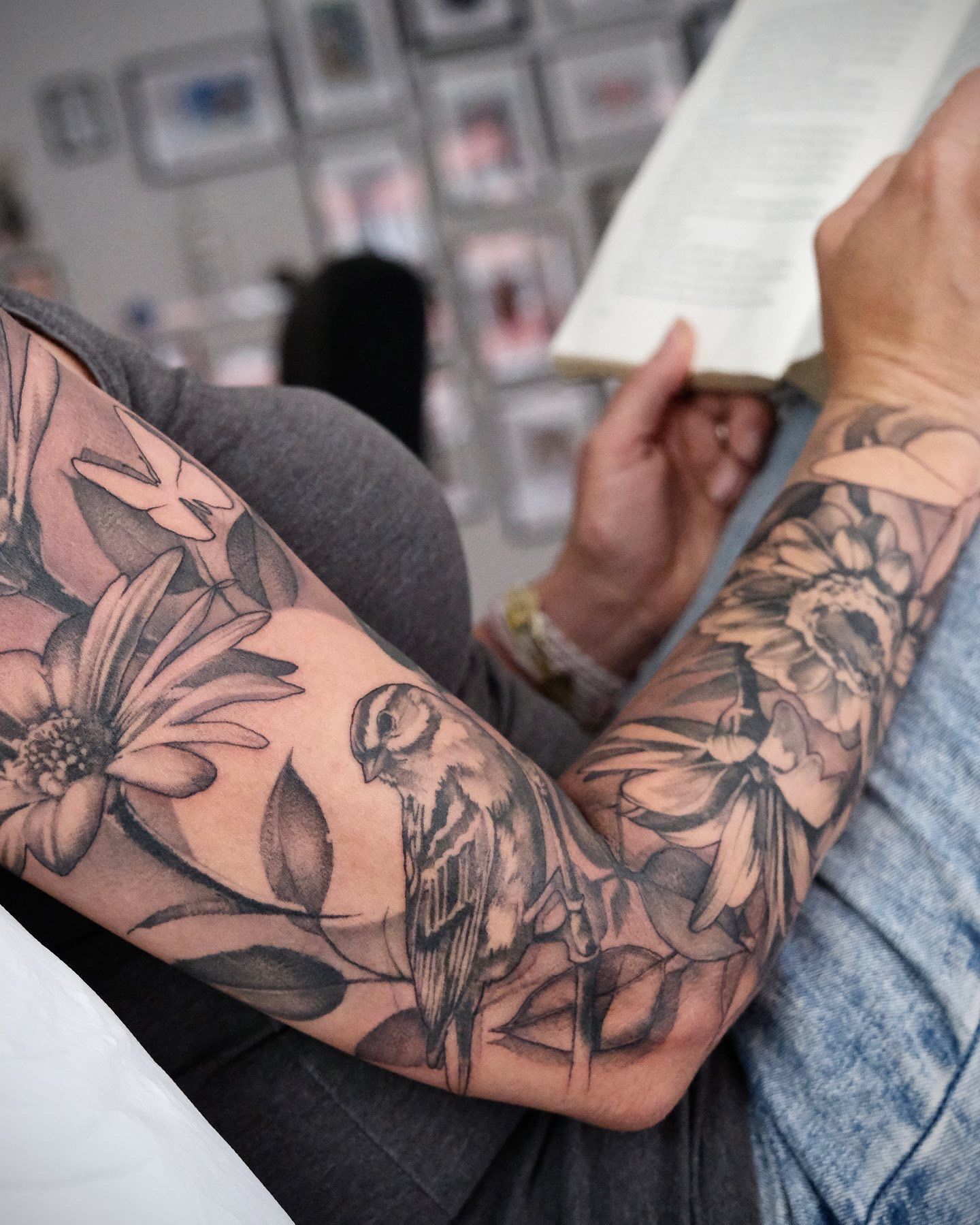 Eine Person mit einer Tätowierung auf dem Arm, die ein Buch liest