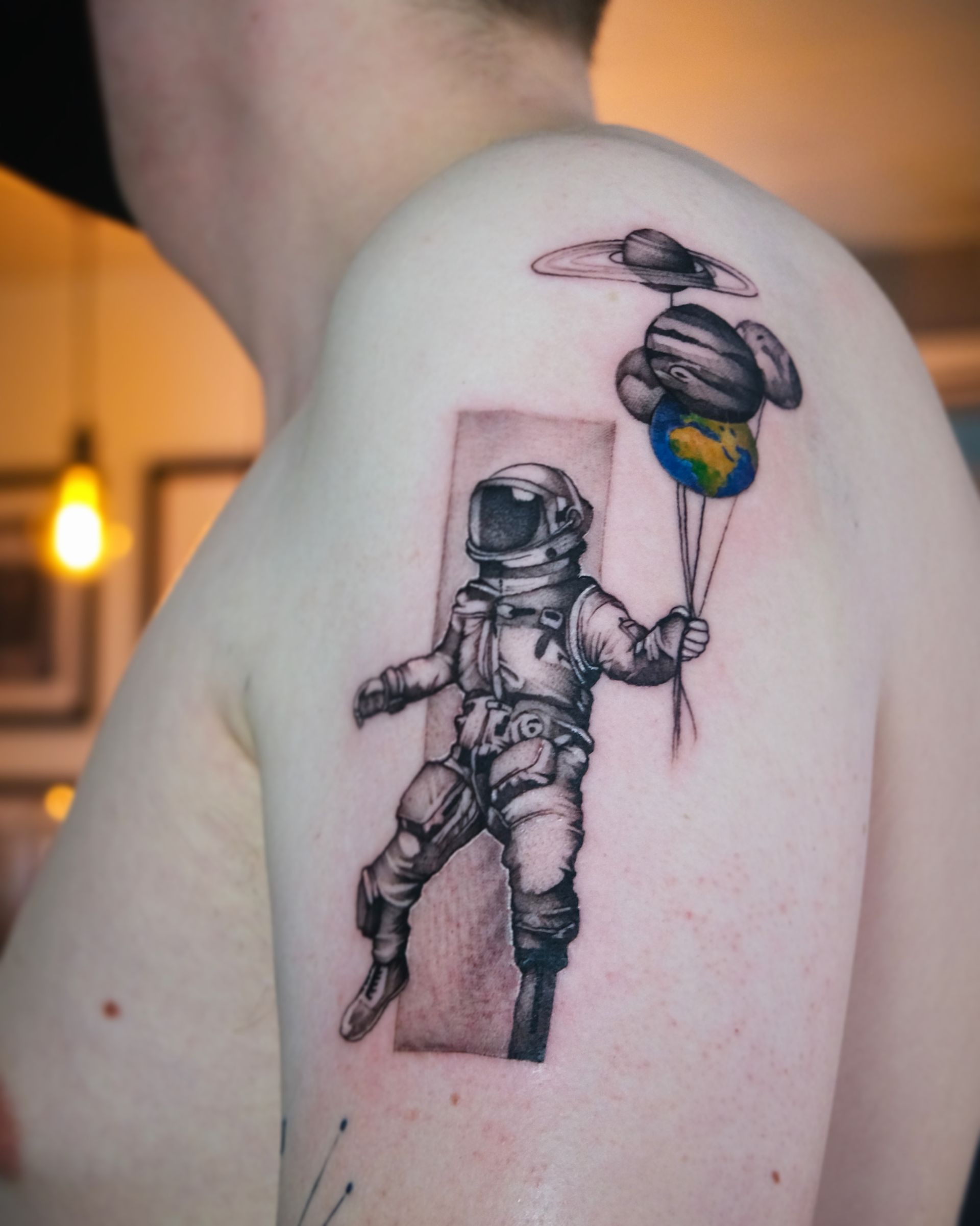 Ein Mann hat ein Tattoo von einem Astronauten, der einen Ballon hält
