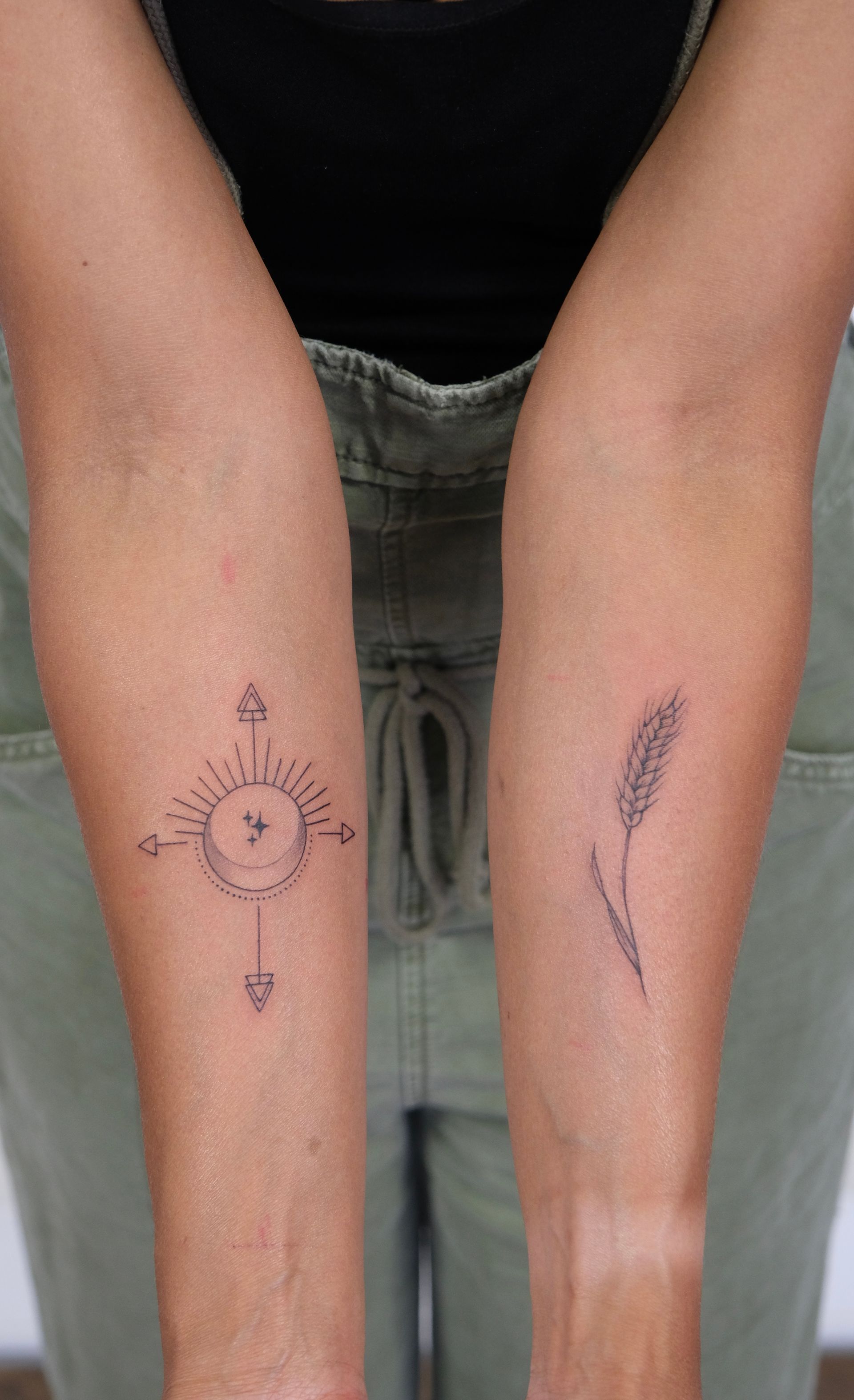 Eine Frau hat eine Tätowierung mit einer Sonne und einer Blume auf ihrem Unterarm.