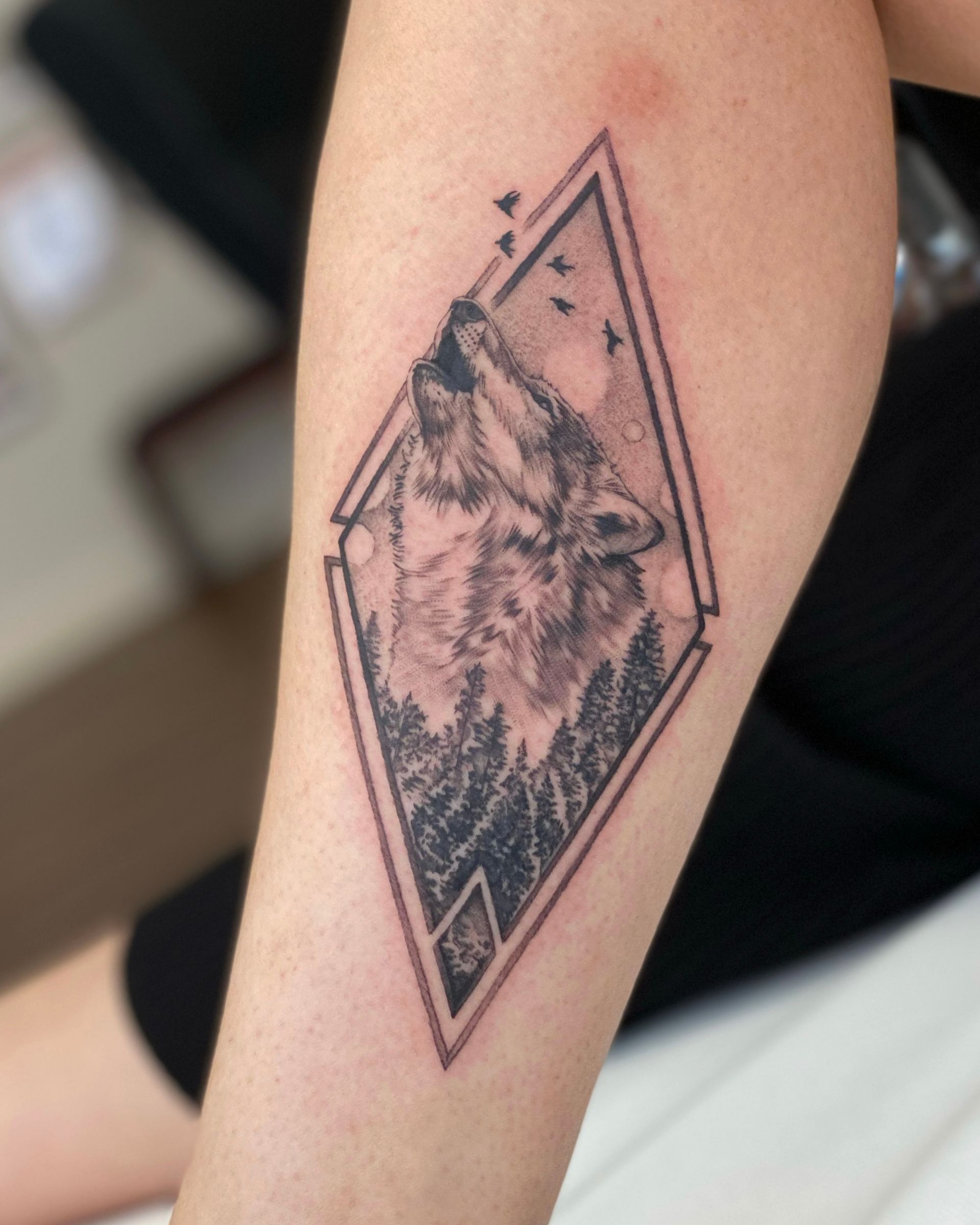 Eine Person hat ein Wolfstattoo auf dem Arm