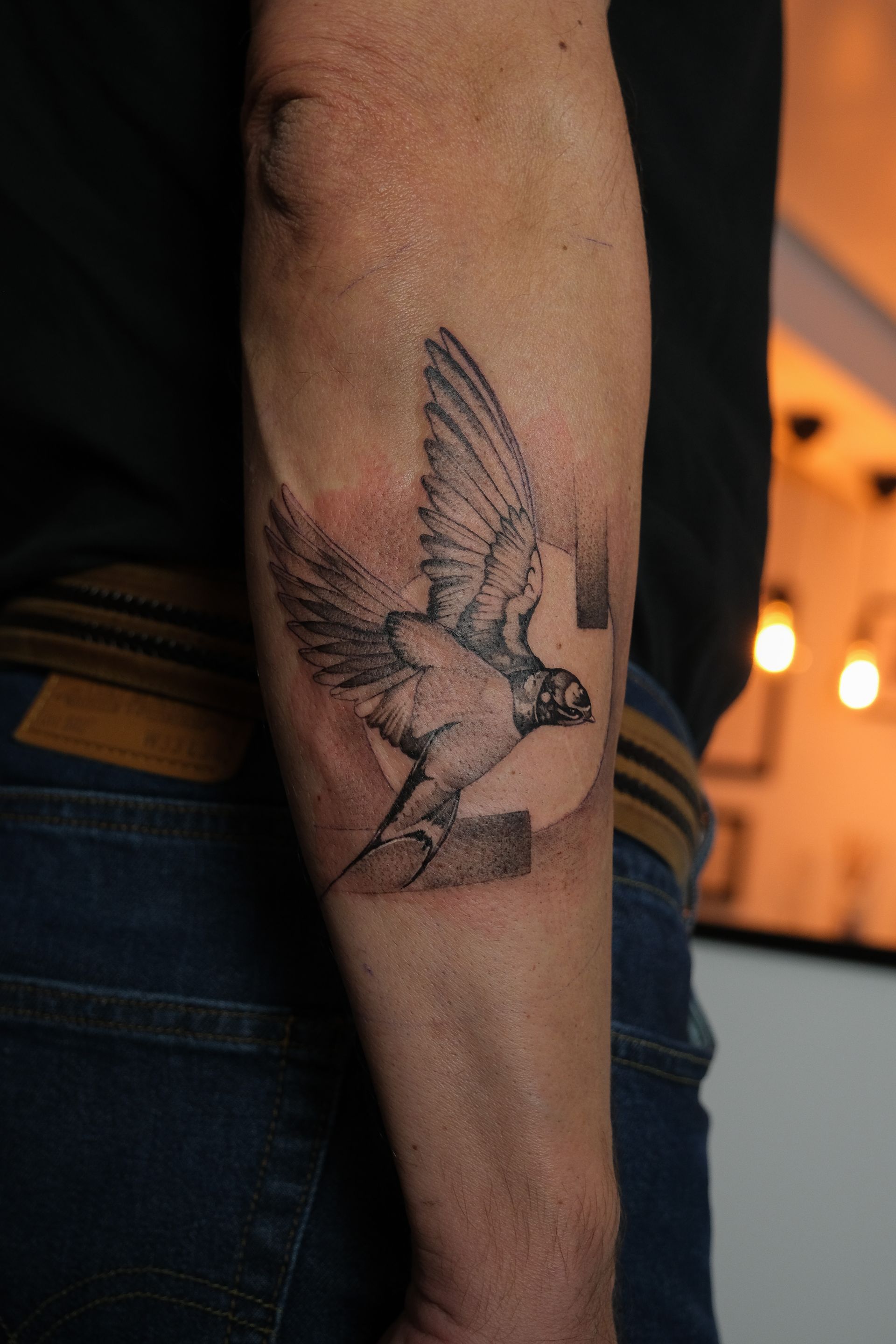 Ein Mann hat ein Vogeltattoo auf seinem Arm