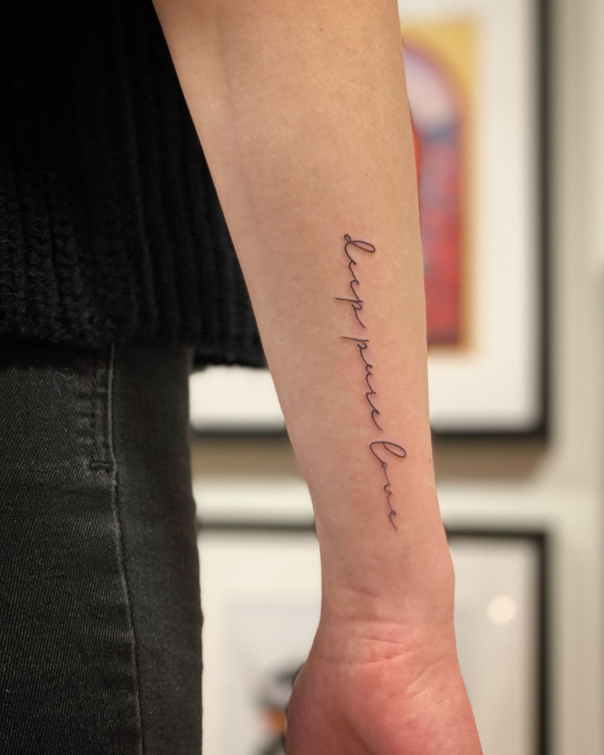 Eine Person hat ein Tattoo auf dem Unterarm, auf dem steht: „Langlebige Liebe“