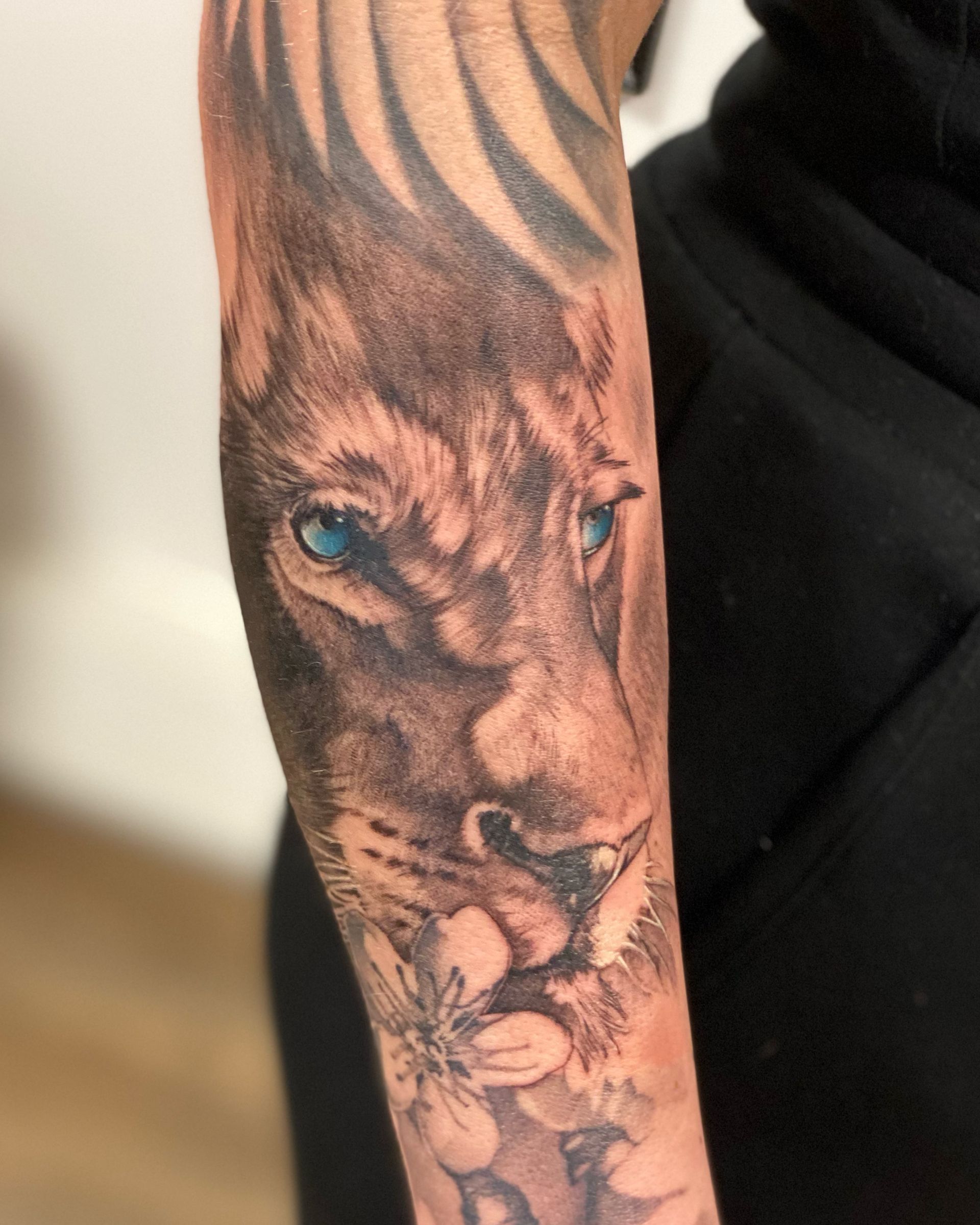 Eine Person hat eine Löwentätowierung auf dem Arm