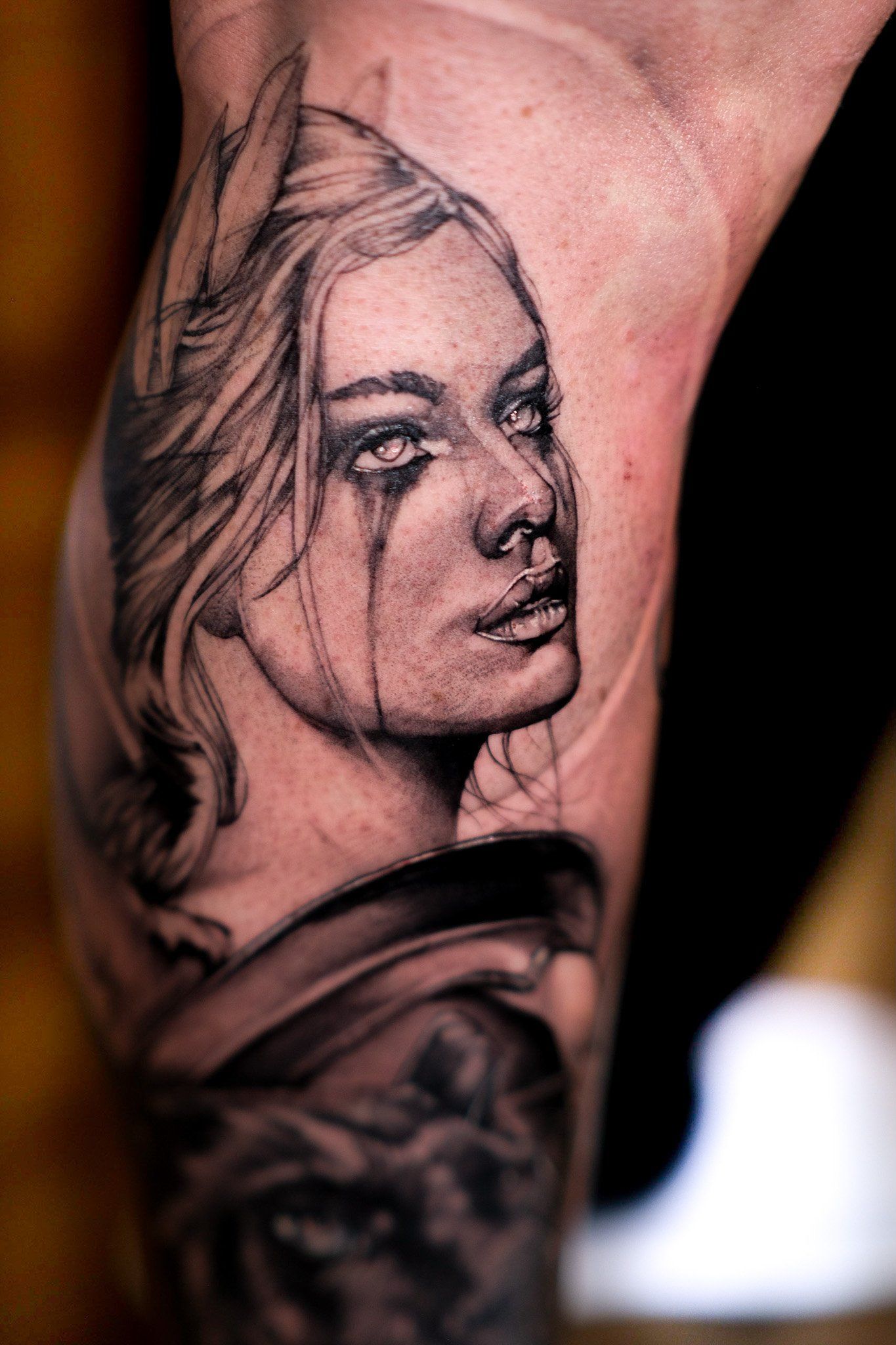 Ein Mann hat ein Tattoo mit dem Gesicht einer Frau auf seinem Bein.