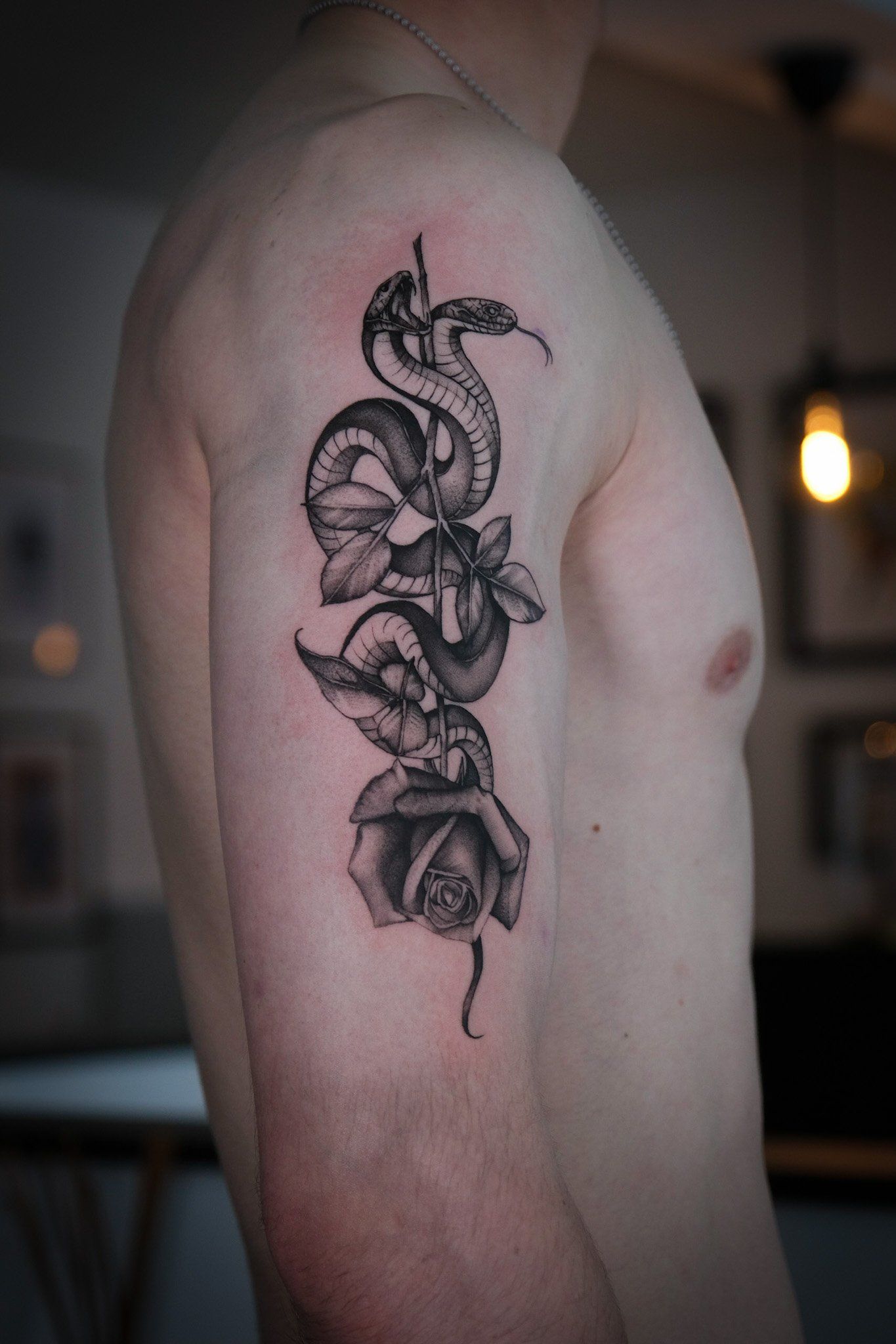 Ein Mann hat eine Tätowierung einer Schlange und einer Rose auf seinem Arm.