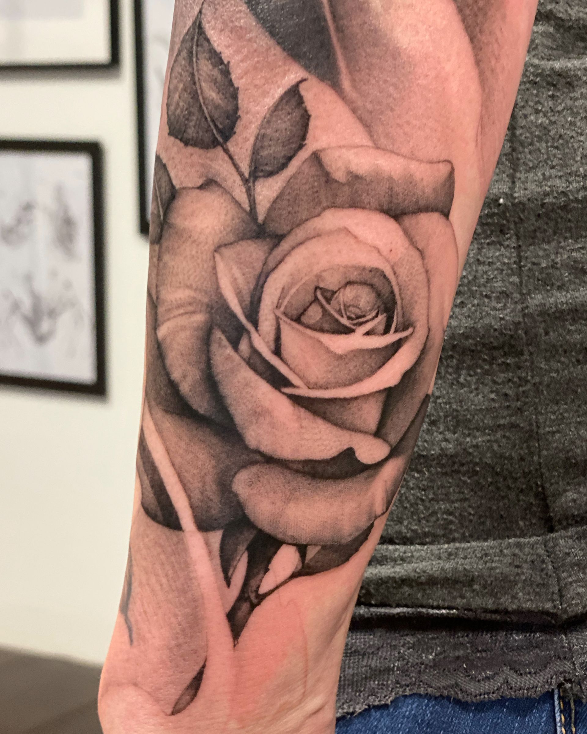 Ein Mann hat eine schwarz-weiße Tätowierung einer Rose auf seinem Unterarm.