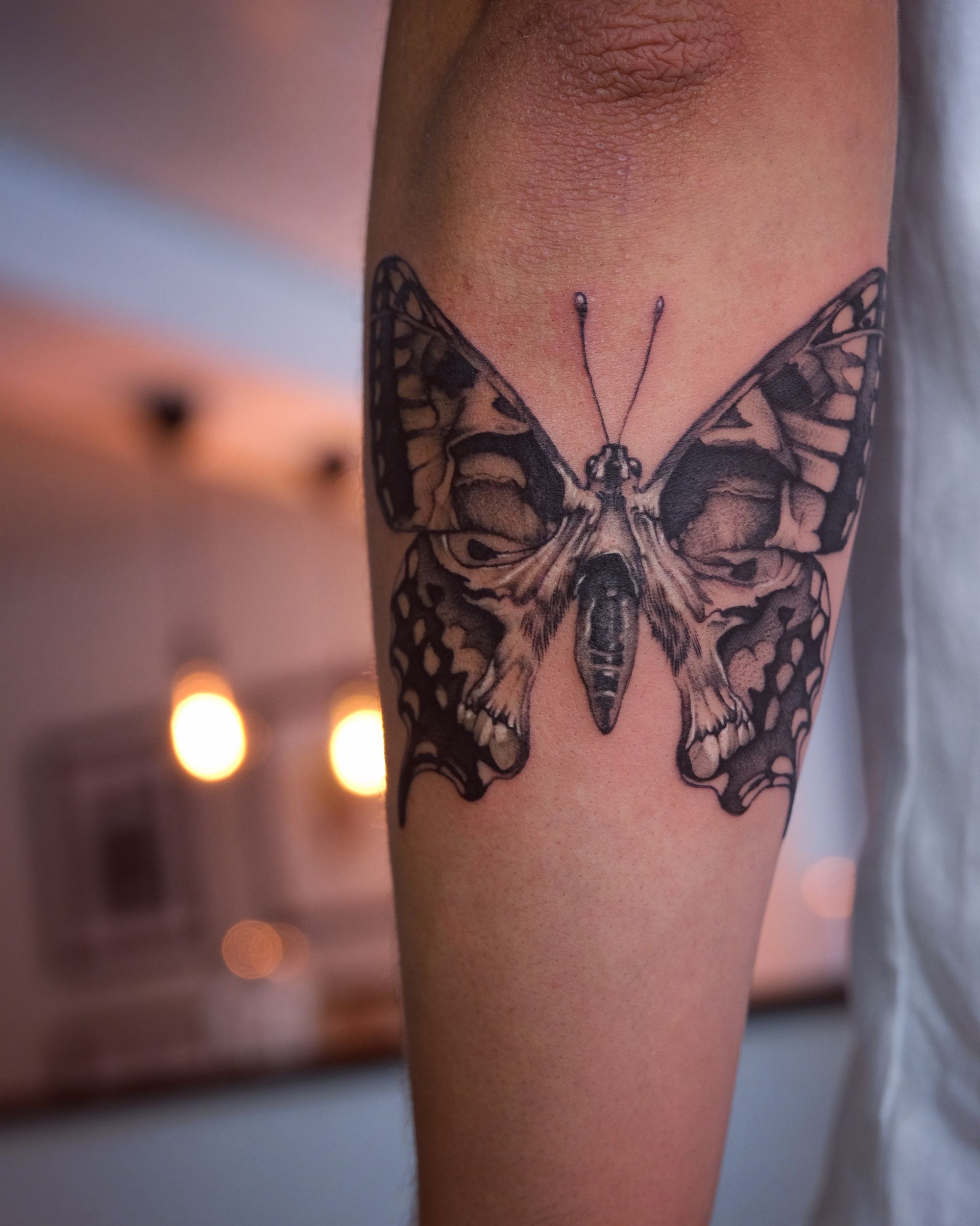 Eine Person hat ein Schmetterlingstattoo auf dem Arm