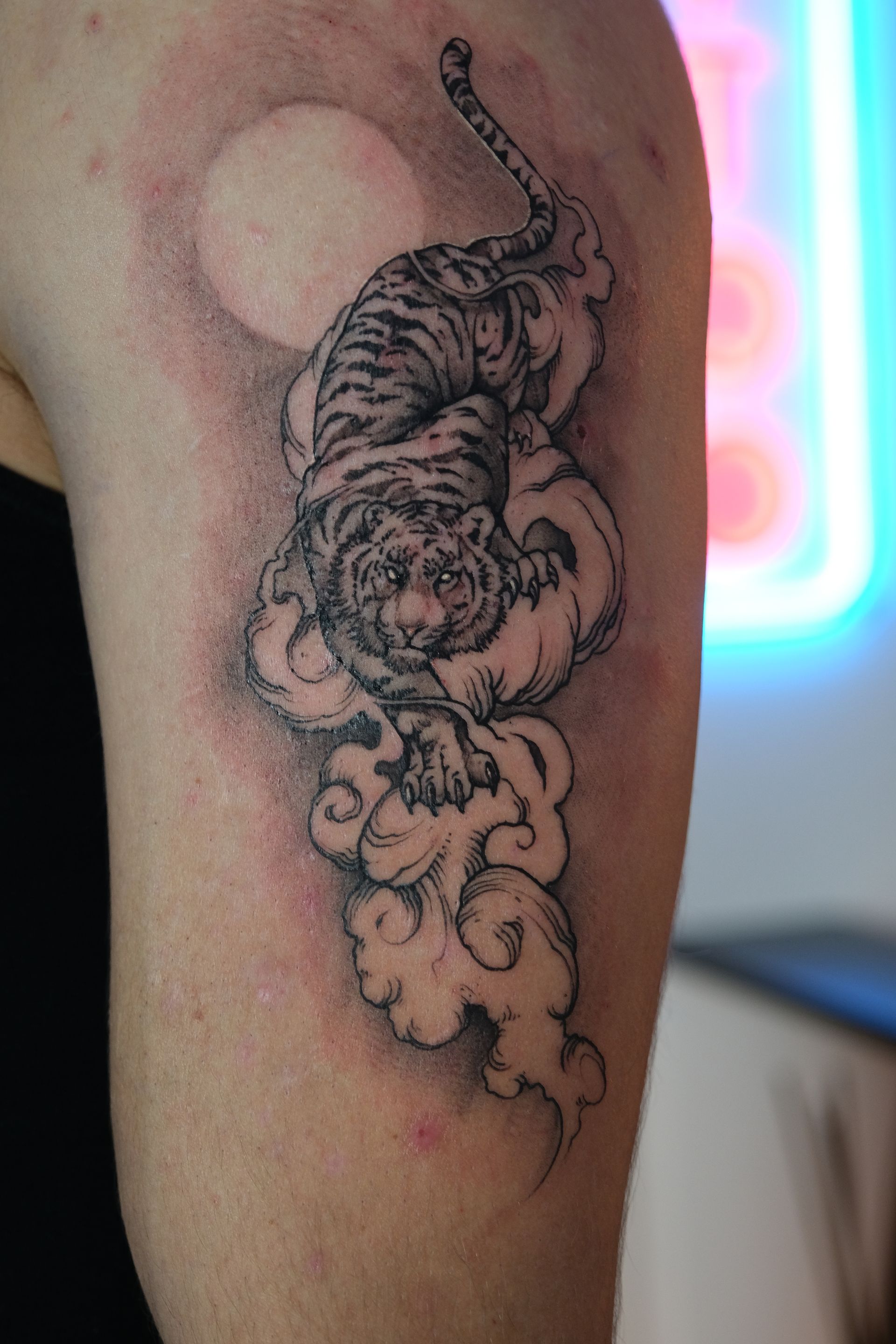 Eine Person hat eine Tigertätowierung auf dem Arm.