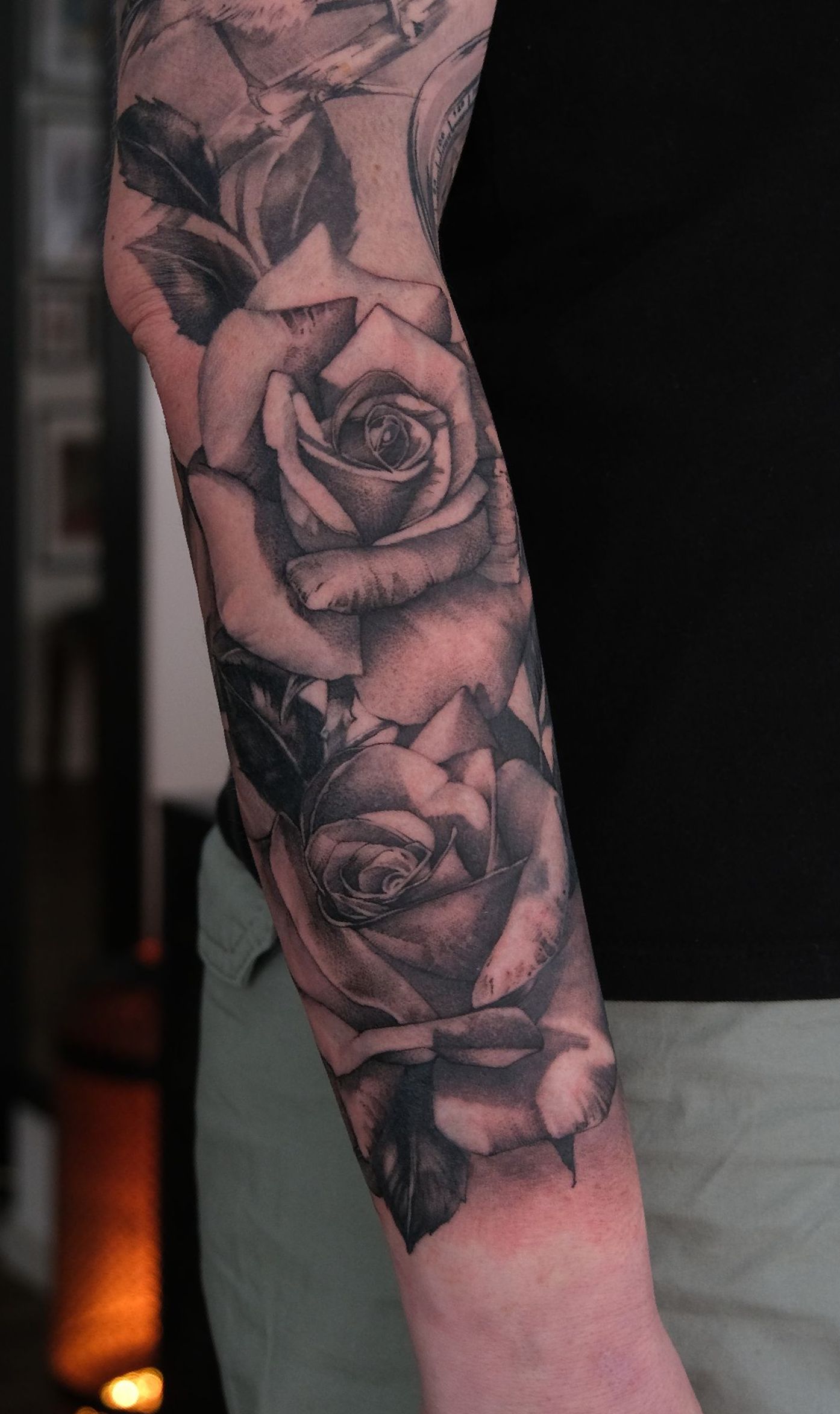 Ein Mann hat eine Tätowierung mit drei Rosen auf seinem Arm.