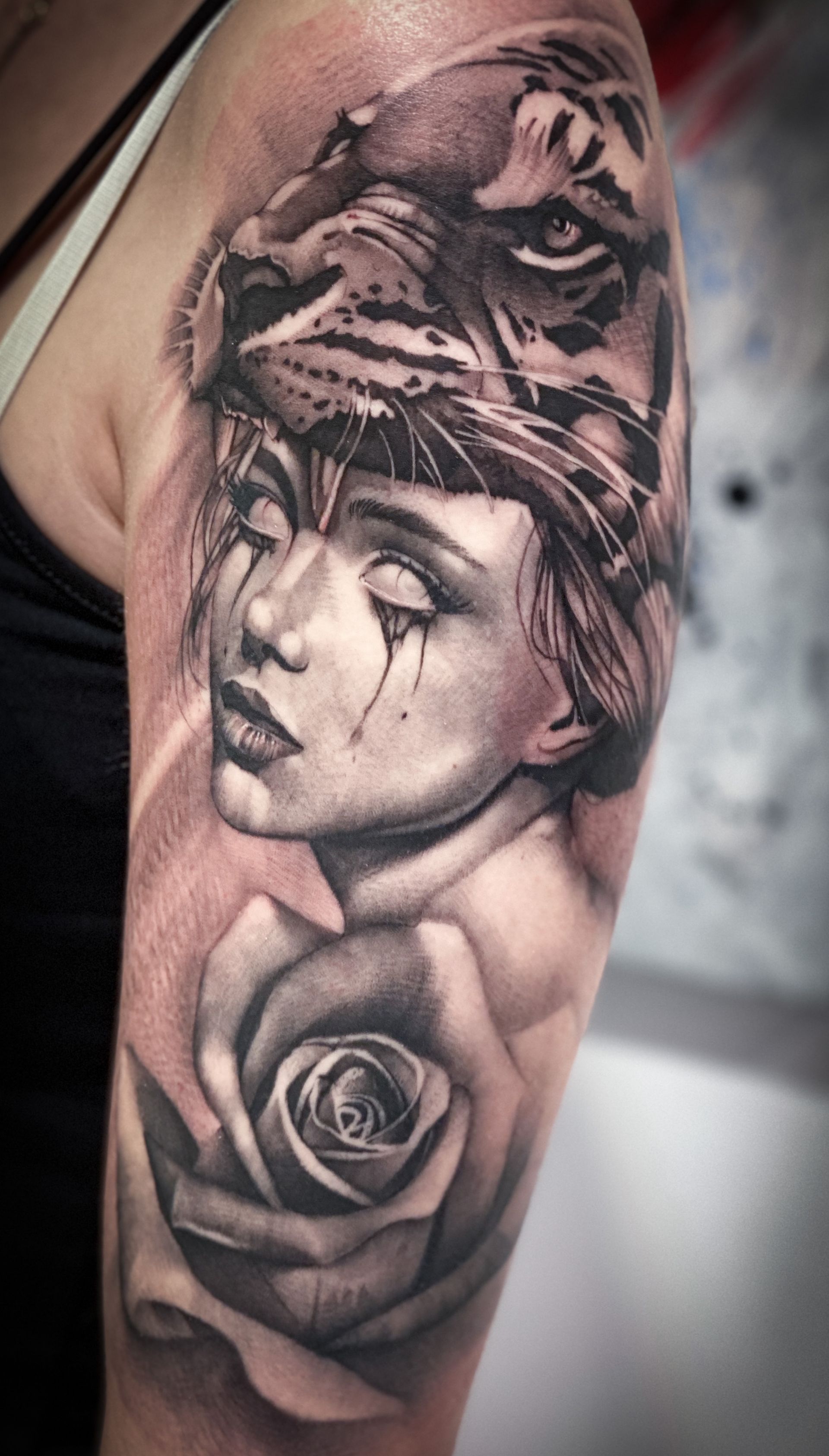 Ein schwarz-weißes Tattoo einer Frau mit einem Tiger auf dem Kopf und einer Rose.