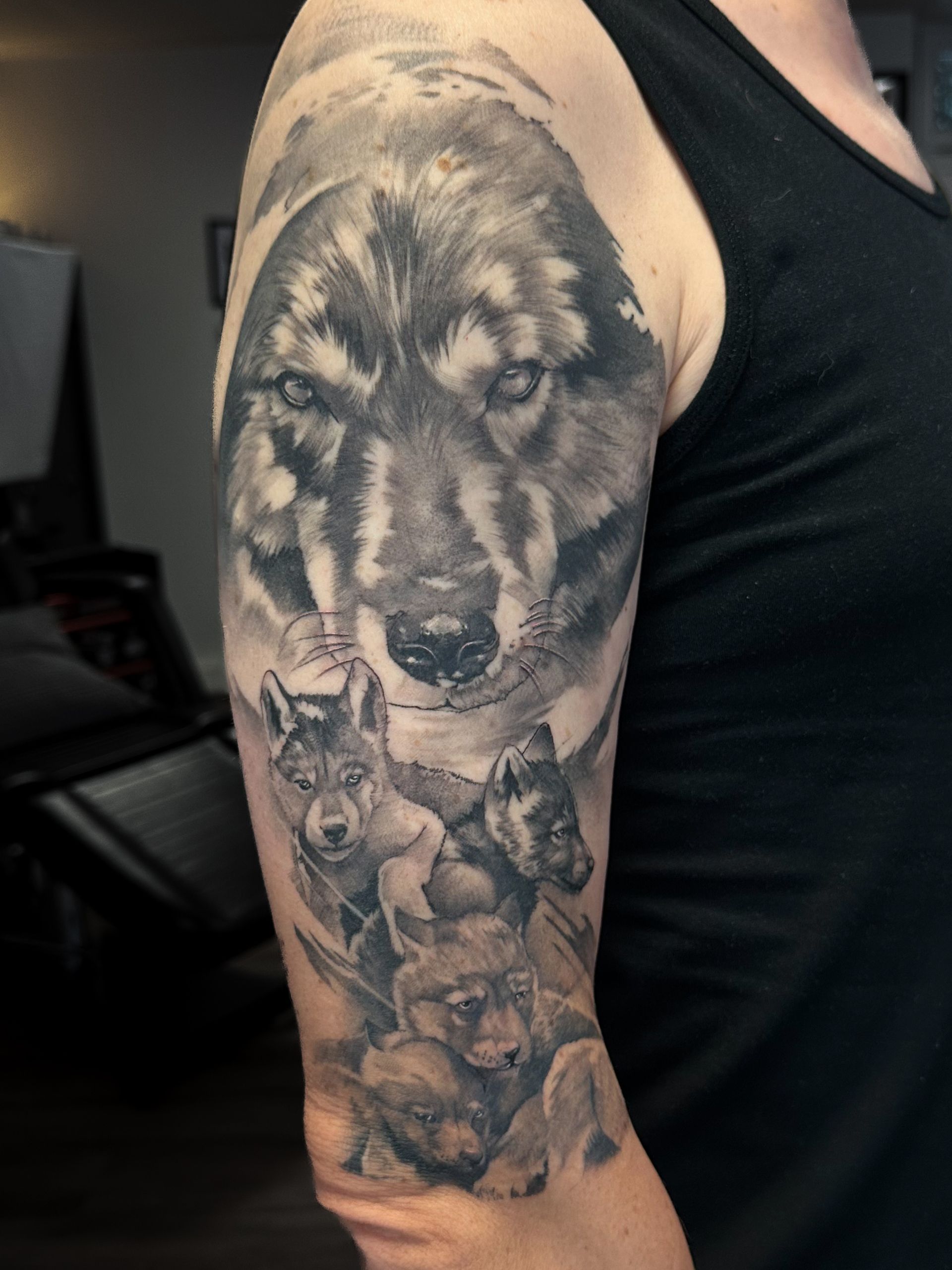 Ein Mann hat eine Tätowierung von einem Wolf und seinen Jungen auf seinem Arm