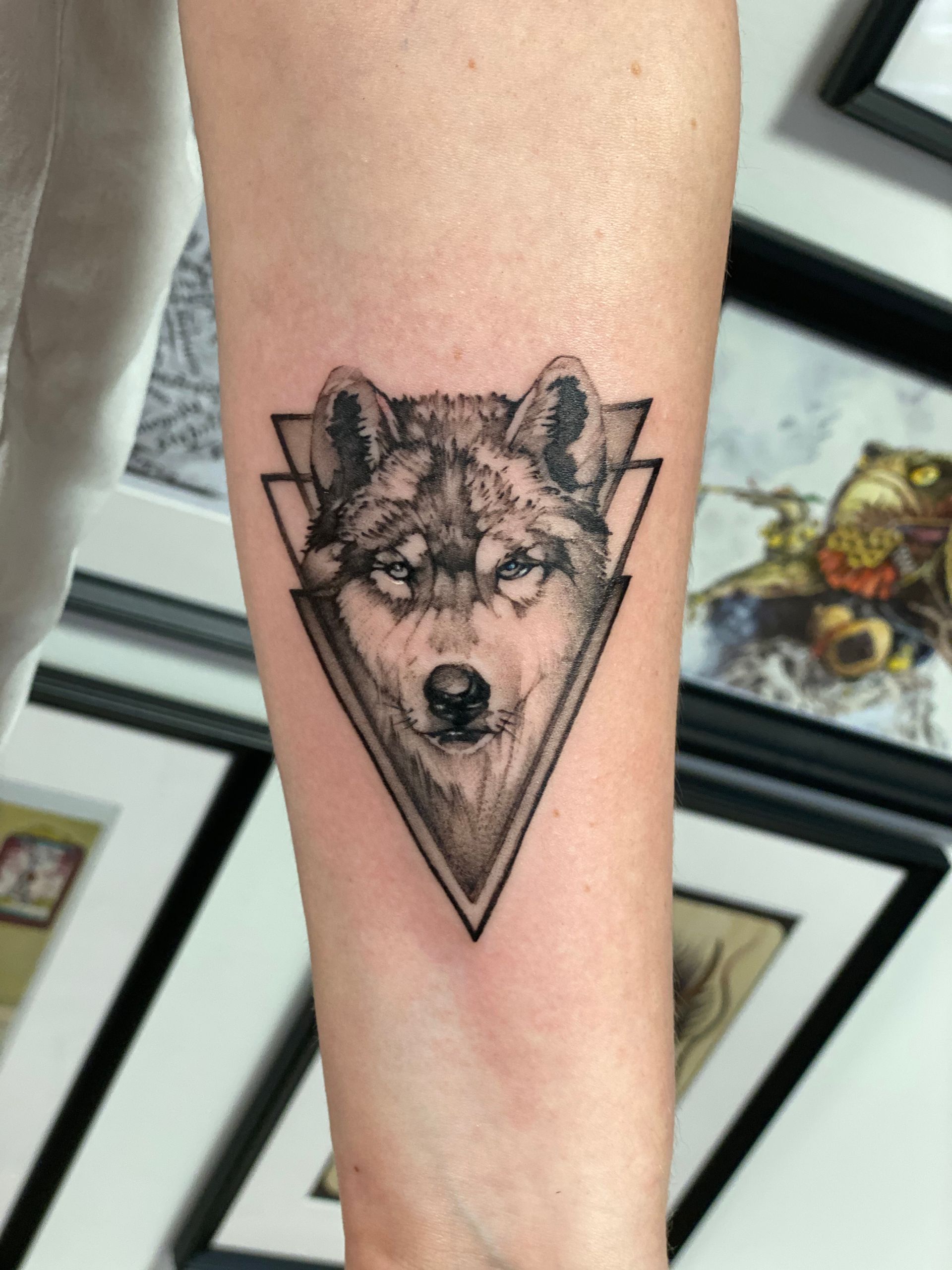 Ein Tattoo eines Wolfskopfes in einem Dreieck