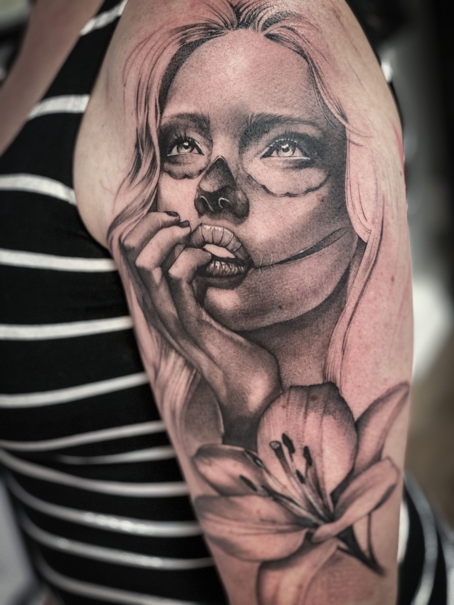 Eine Frau hat eine Tätowierung einer Frau mit einer Blume auf ihrem Arm