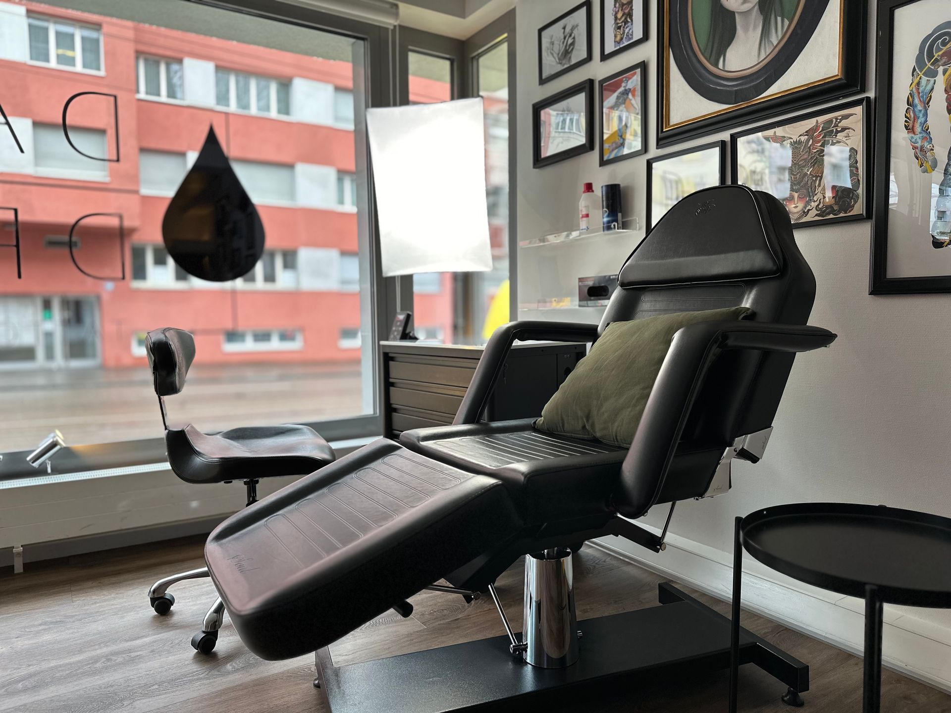 In einem Raum mit vielen Bildern an der Wand steht ein Tattoo-Stuhl.