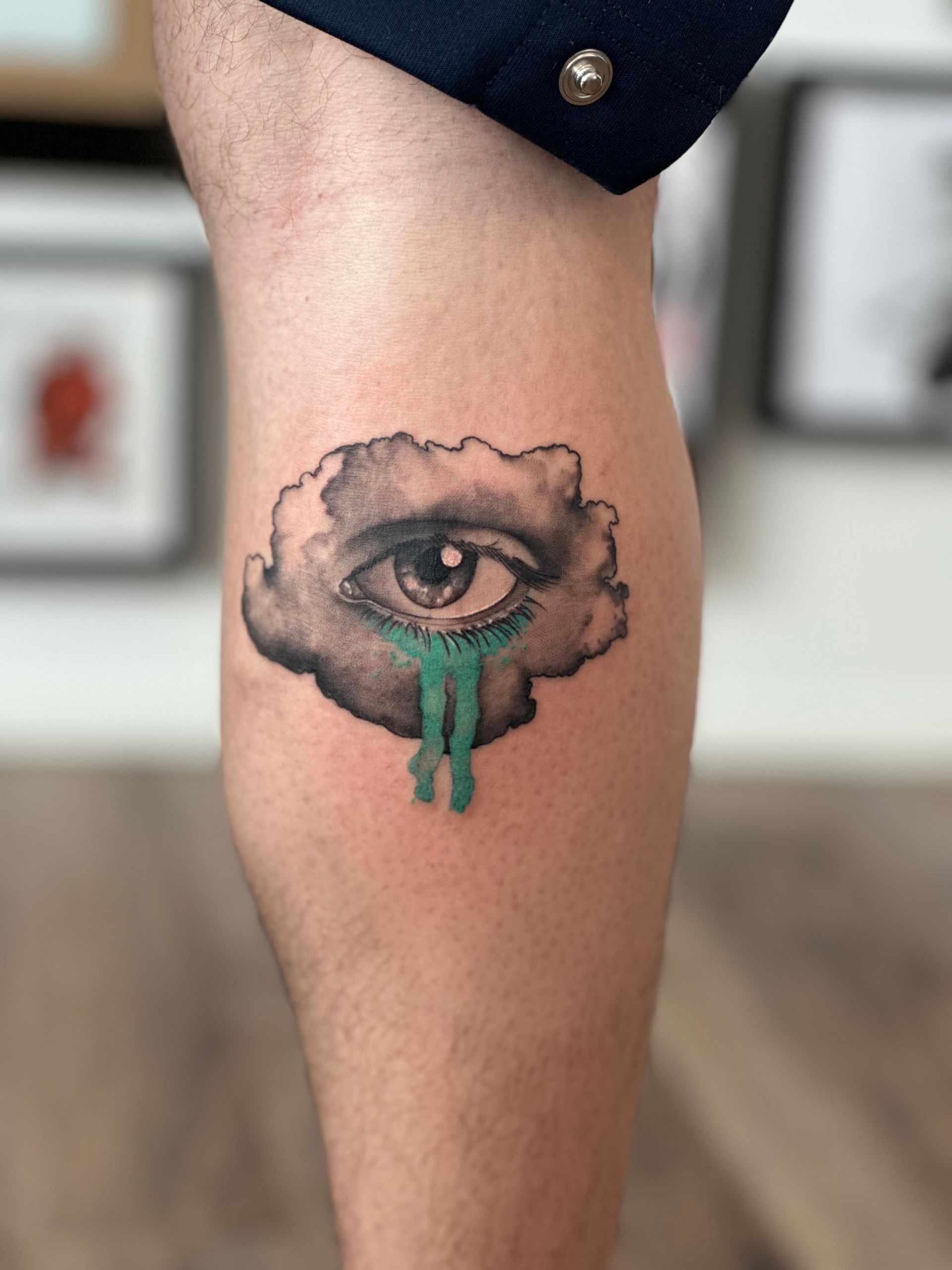 Eine Person hat eine Tätowierung eines Auges in einer Wolke auf ihrem Bein.