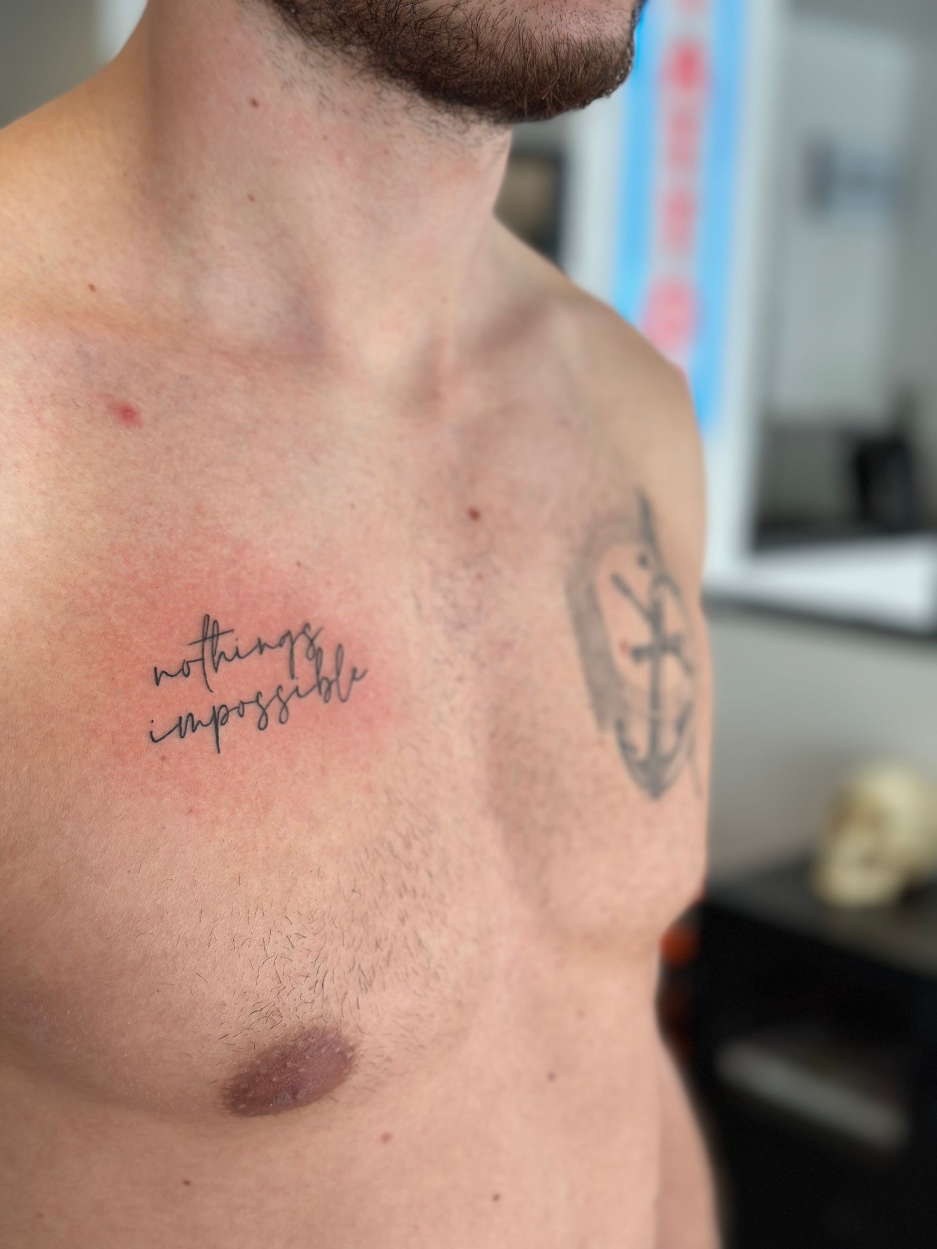 Ein Mann hat eine Tätowierung auf der Brust, auf der steht, dass nichts unmöglich ist.