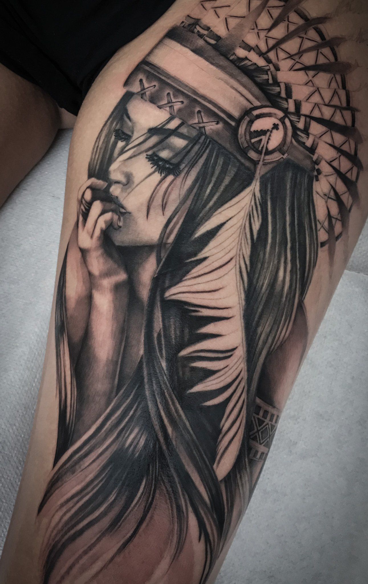Ein schwarz-weißes Tattoo einer Frau mit indianischem Kopfschmuck.