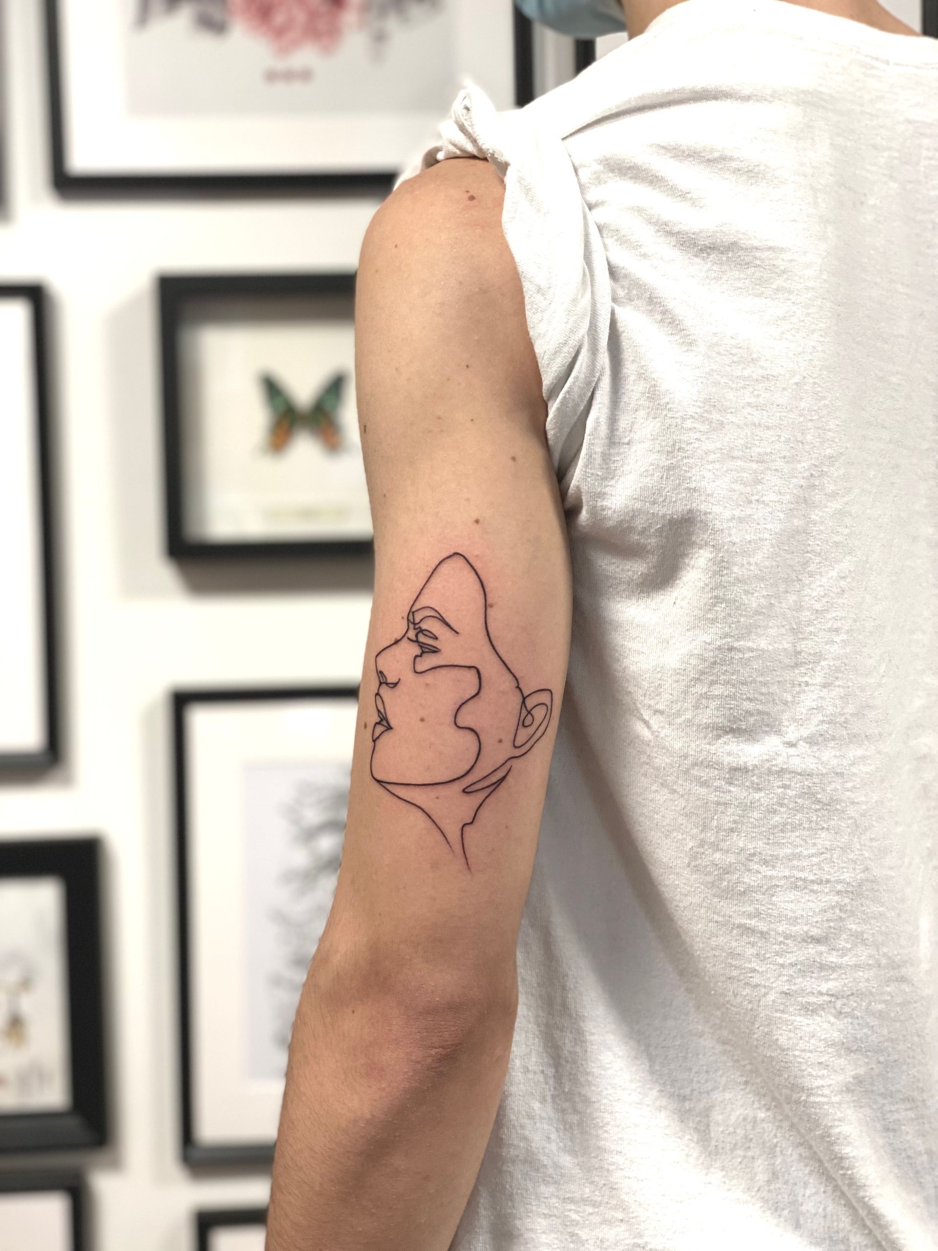 Eine Frau hat ein Tattoo mit einem Frauengesicht auf ihrem Arm.