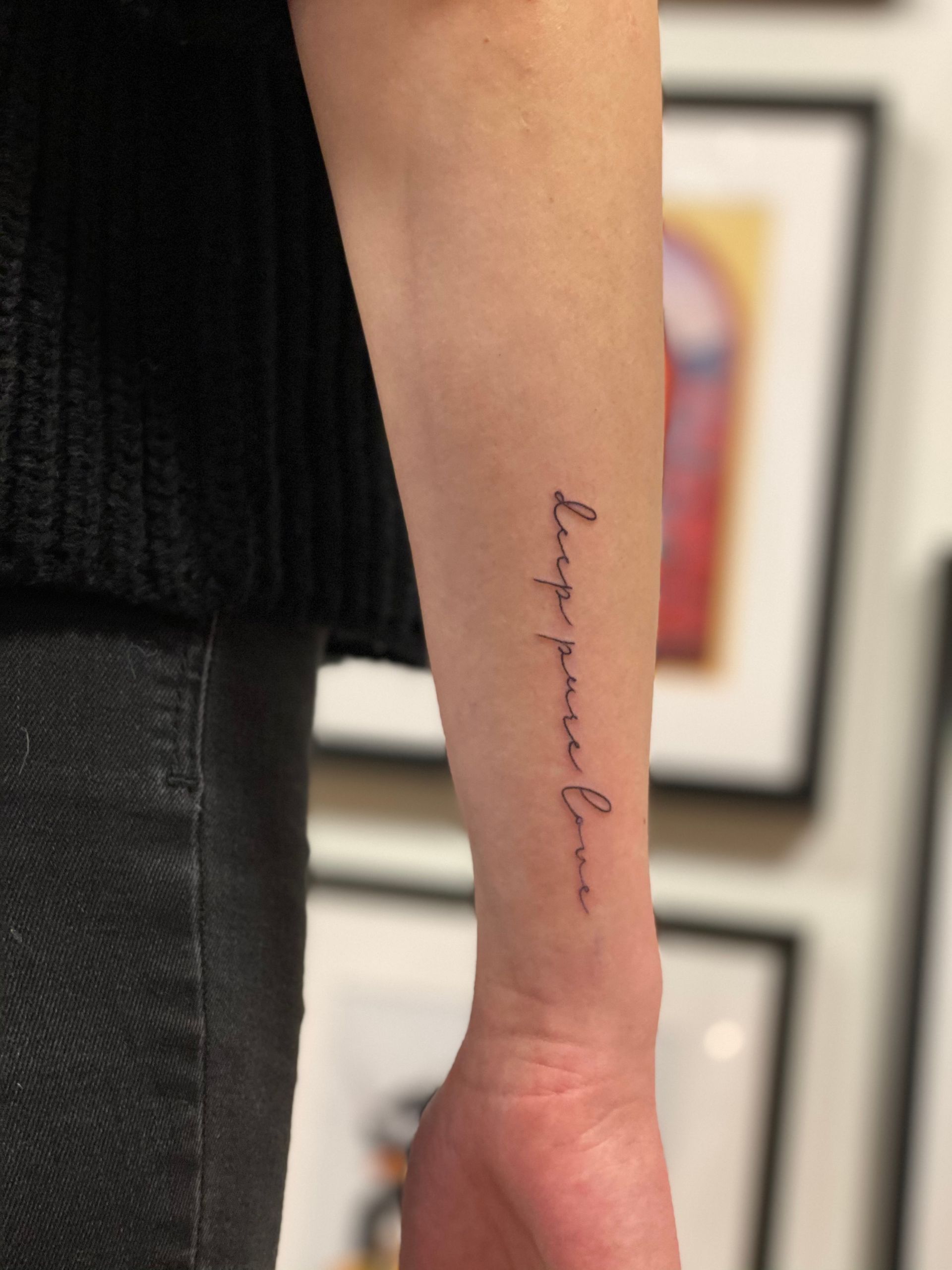Eine Person hat eine Tätowierung am Handgelenk mit der Aufschrift „Behalte deine Liebe“.