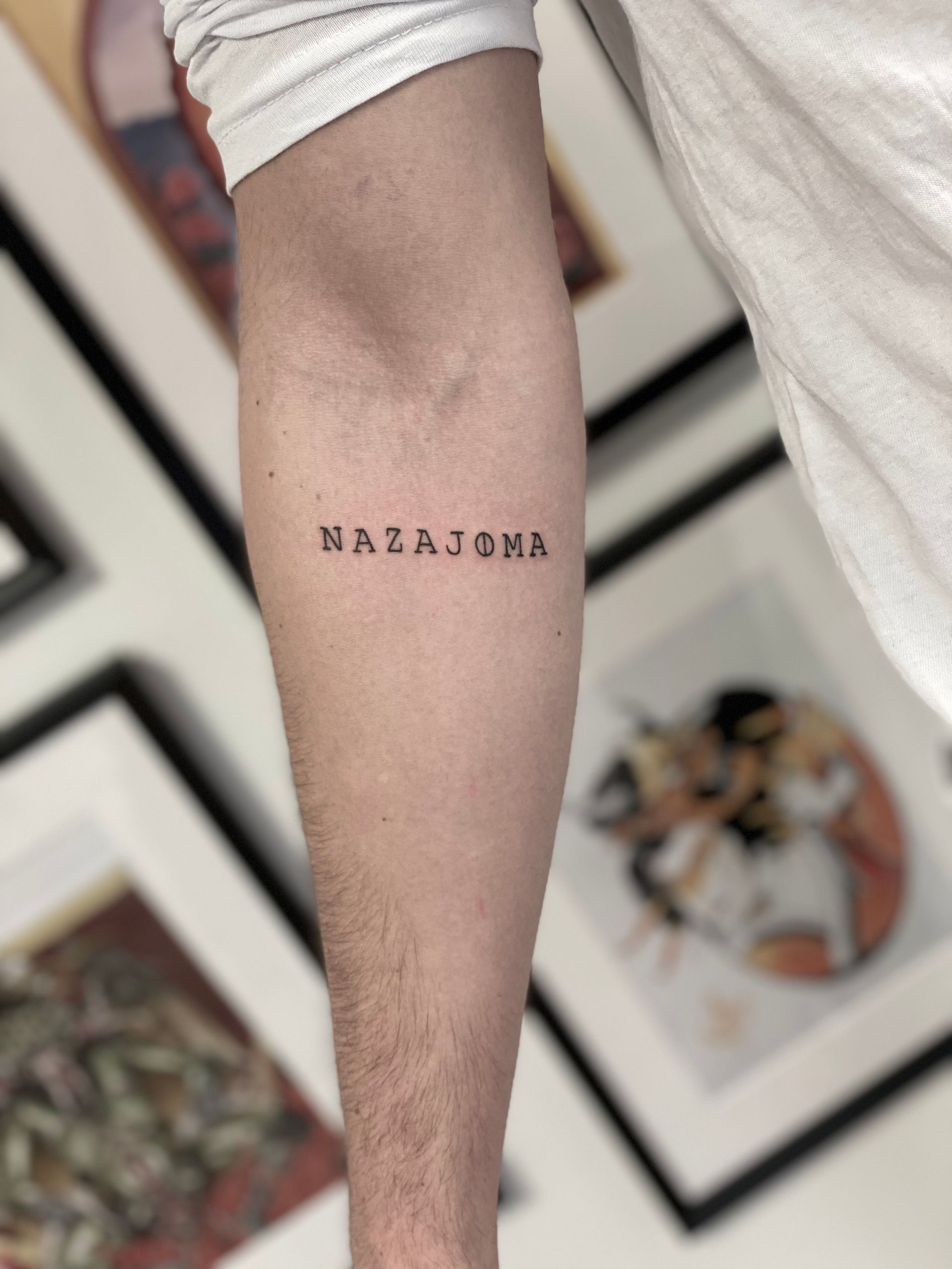 Ein Mann hat ein kleines Tattoo auf seinem Unterarm mit der Aufschrift „Nazarona“