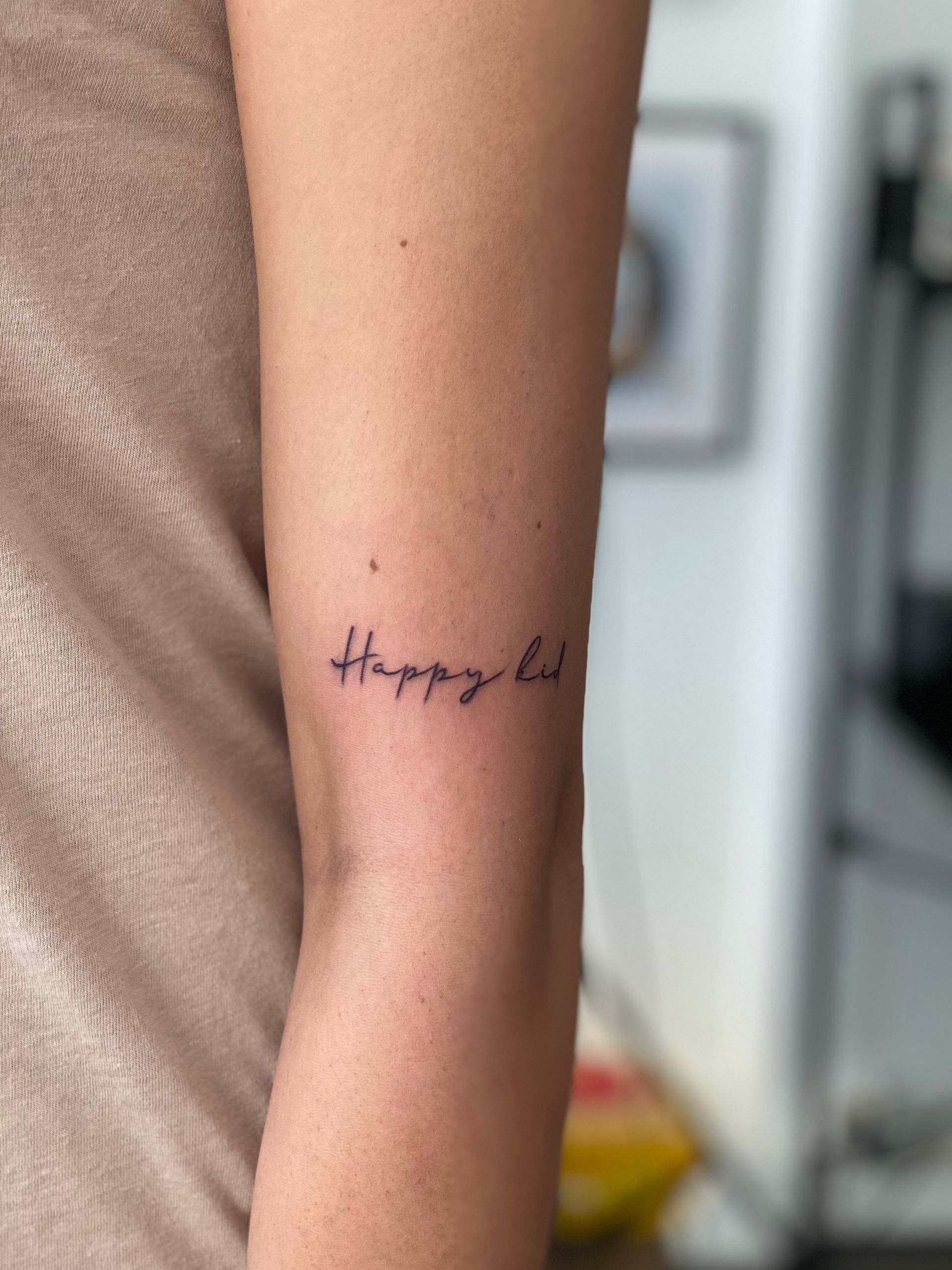 Eine Frau hat ein Tattoo auf ihrem Arm mit der Aufschrift „Happy Life“