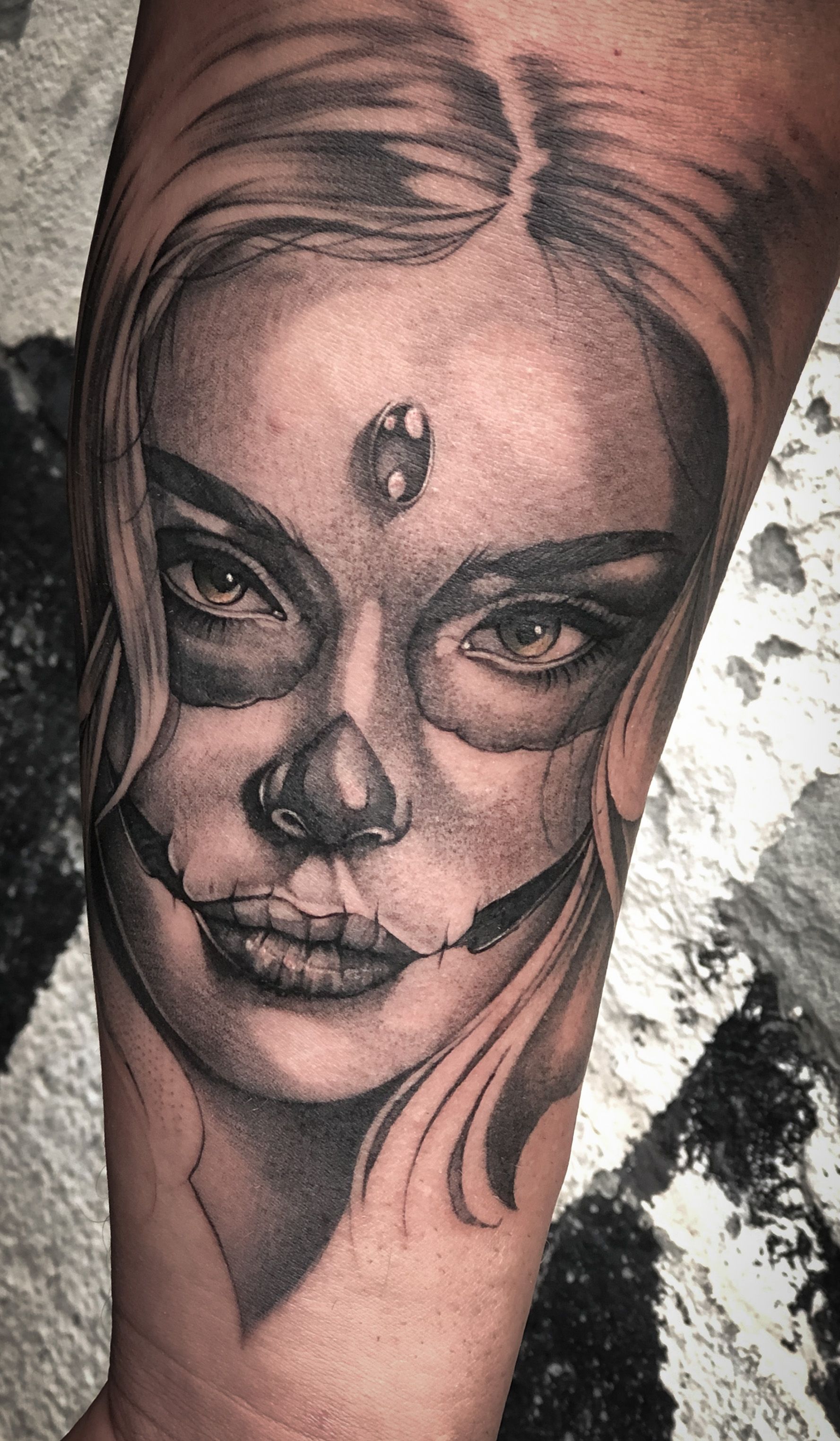 Ein schwarz-weißes Tattoo einer Frau mit einem Totenkopf im Gesicht.