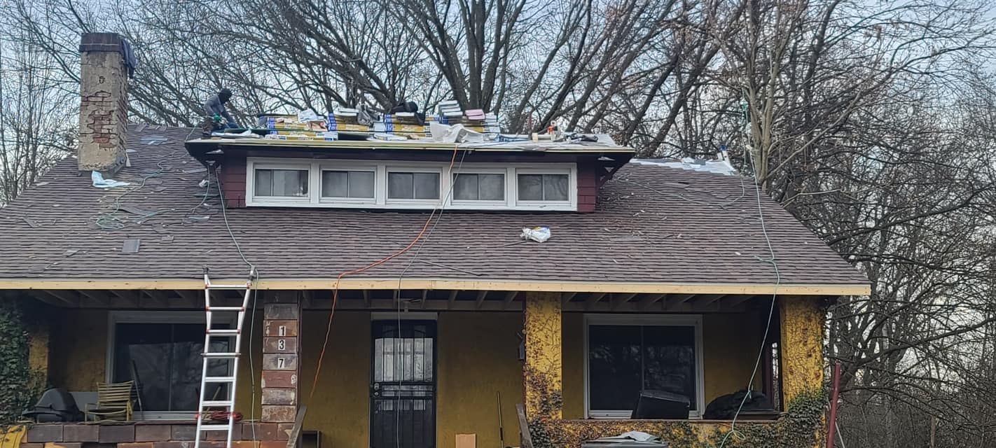 Single-story house with yellow walls, brown roof, and two ladders leaning against the front porch