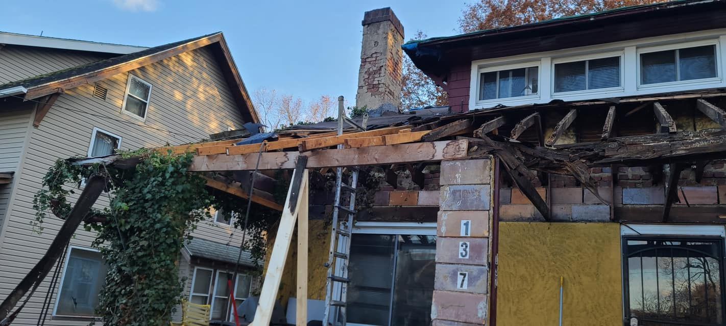 Damaged building exterior with a partially collapsed roof and exposed wooden beams