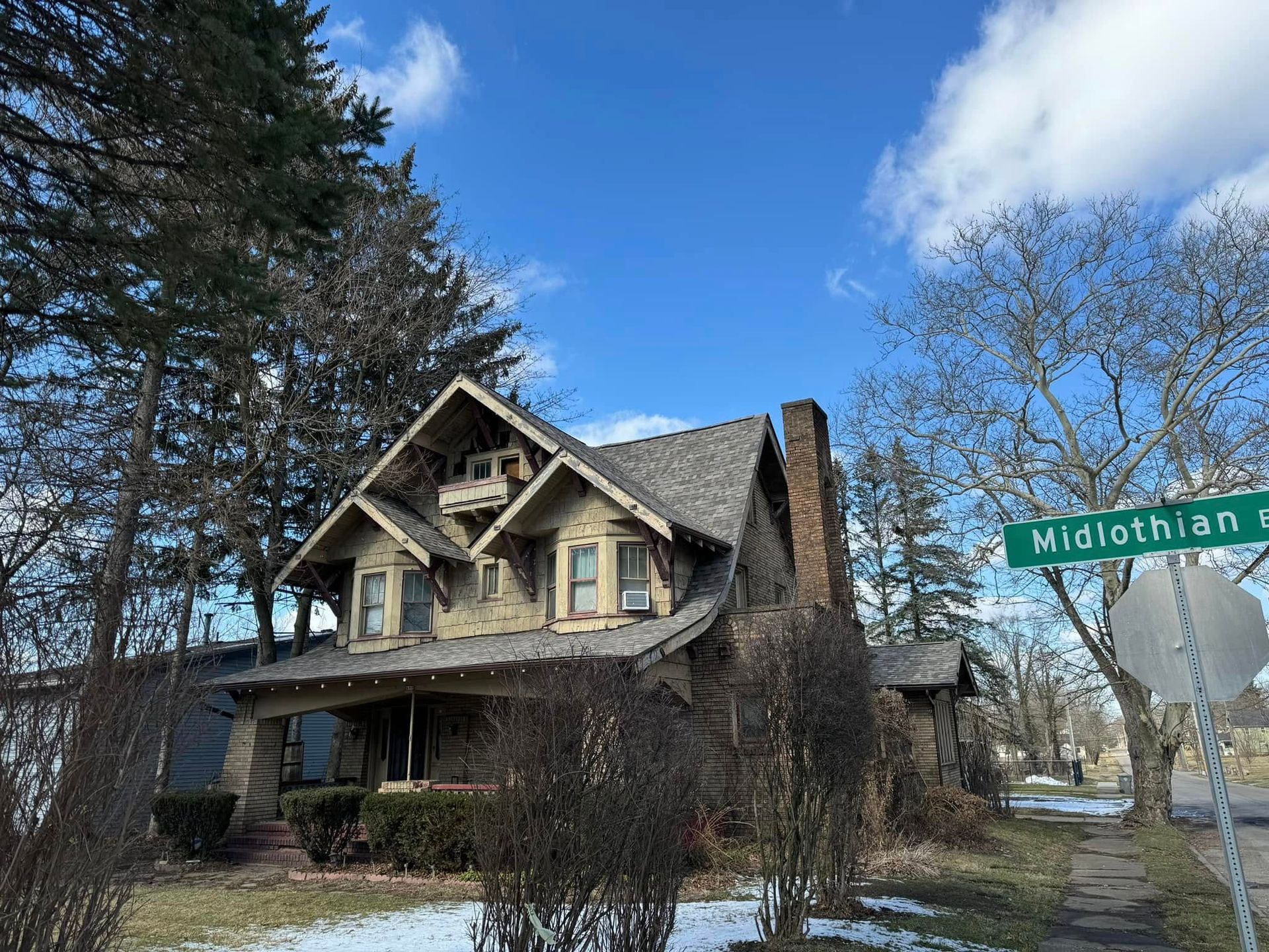 Old house with steep gables beside a street sign under a bright blue sky