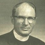 A black and white photo of a man wearing glasses and a clergy collar.