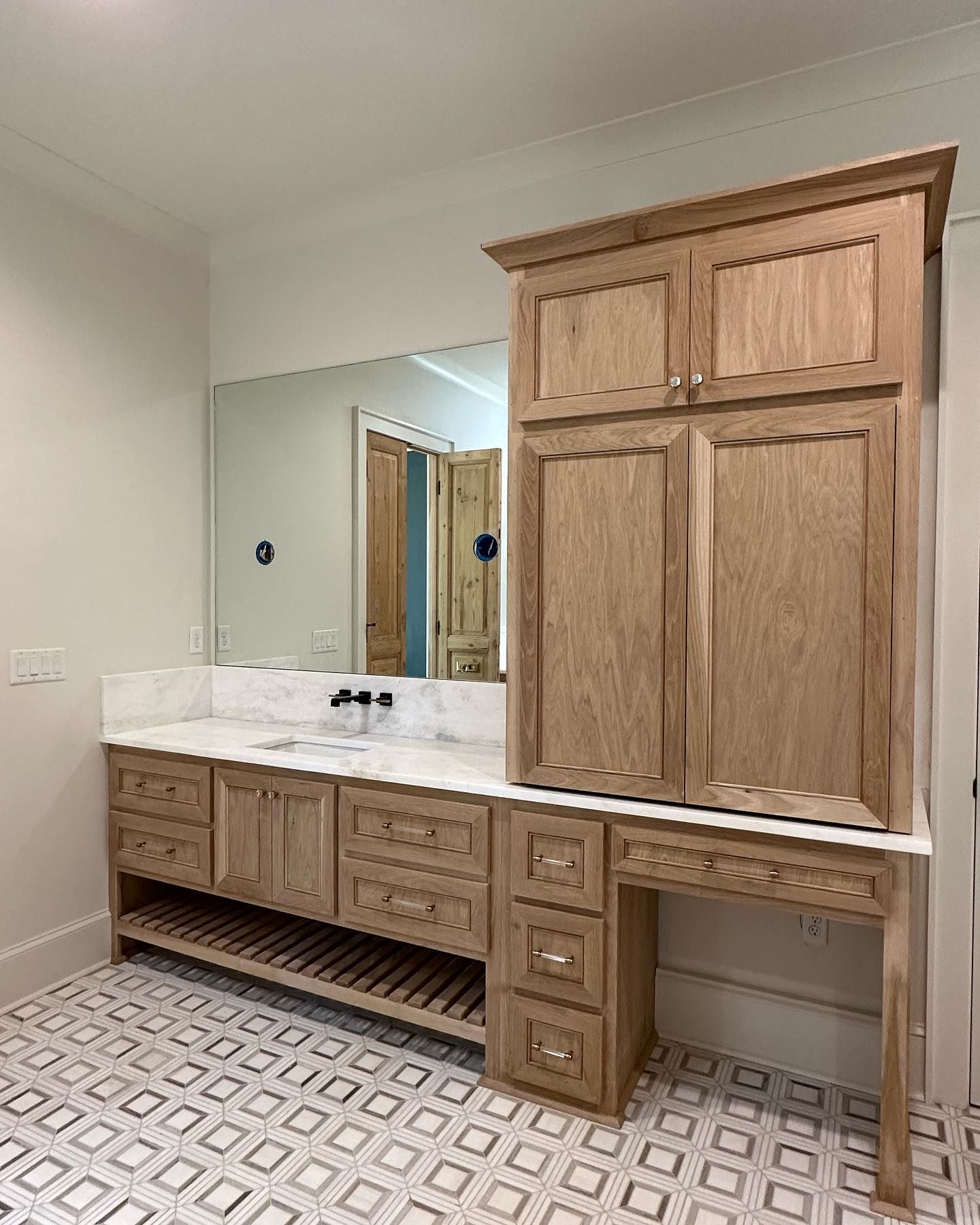 A bathroom with two sinks , a large mirror , and wooden cabinets.