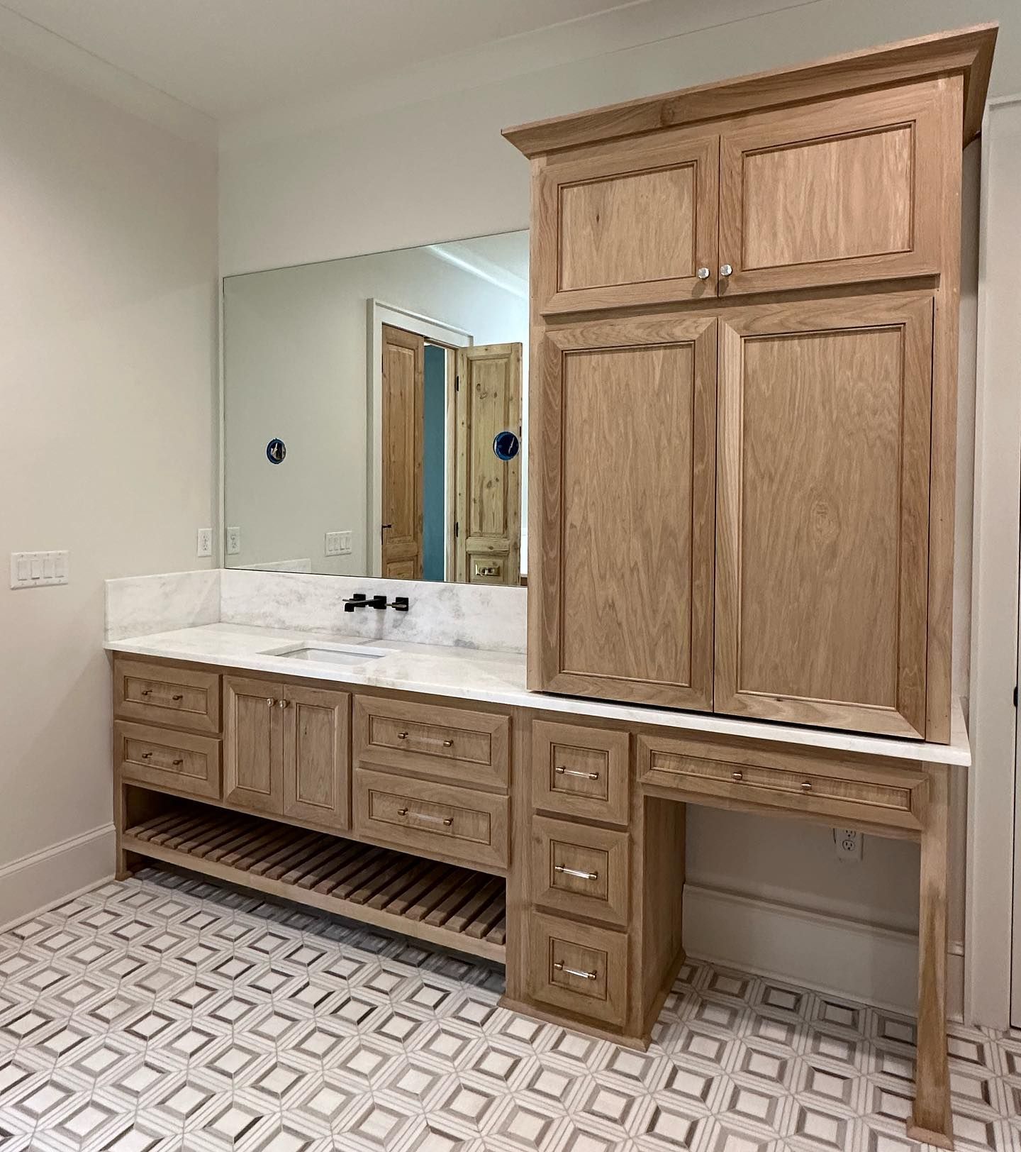A bathroom with a sink , cabinets , and a mirror.