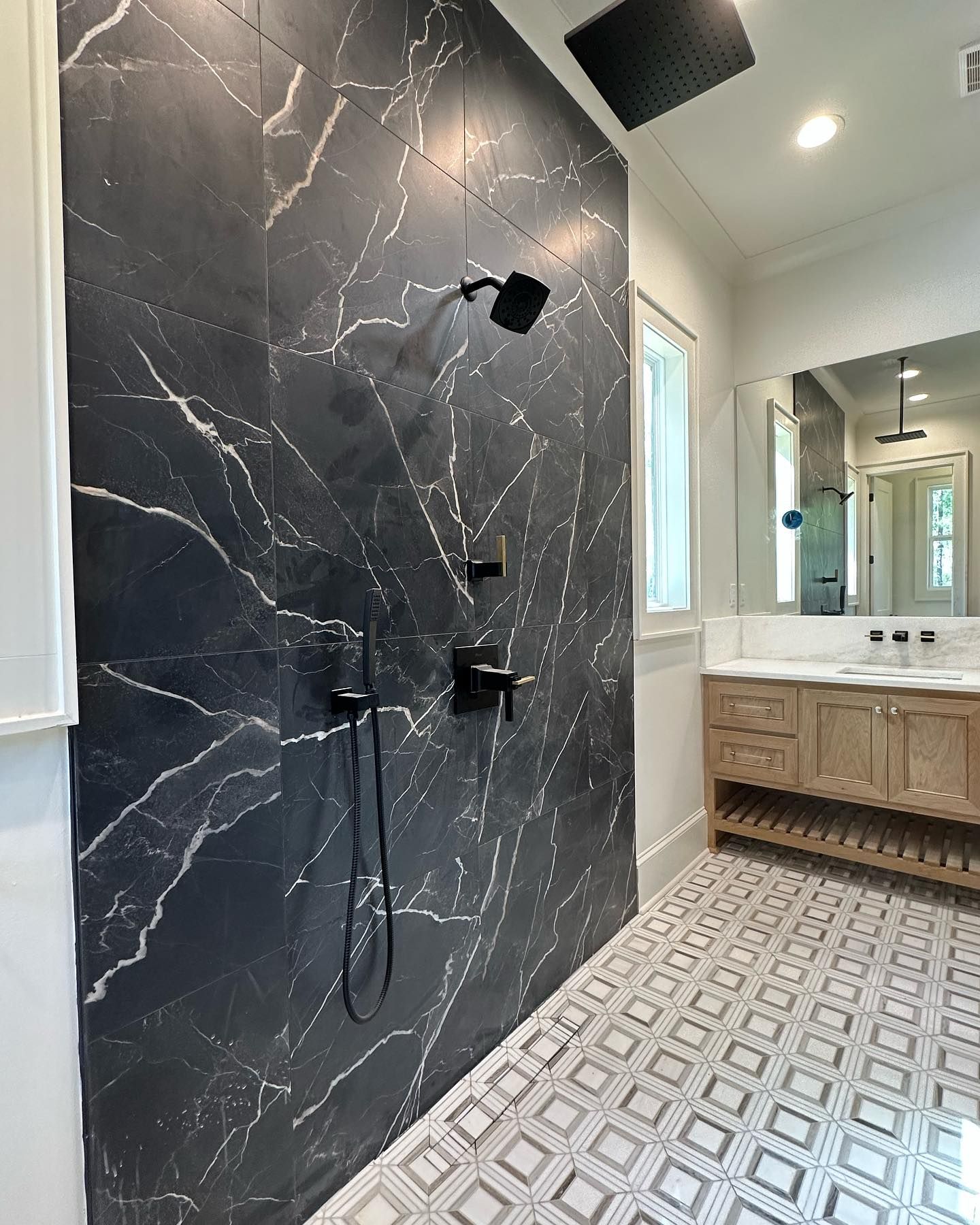 A bathroom with a black marble wall and a black shower head.