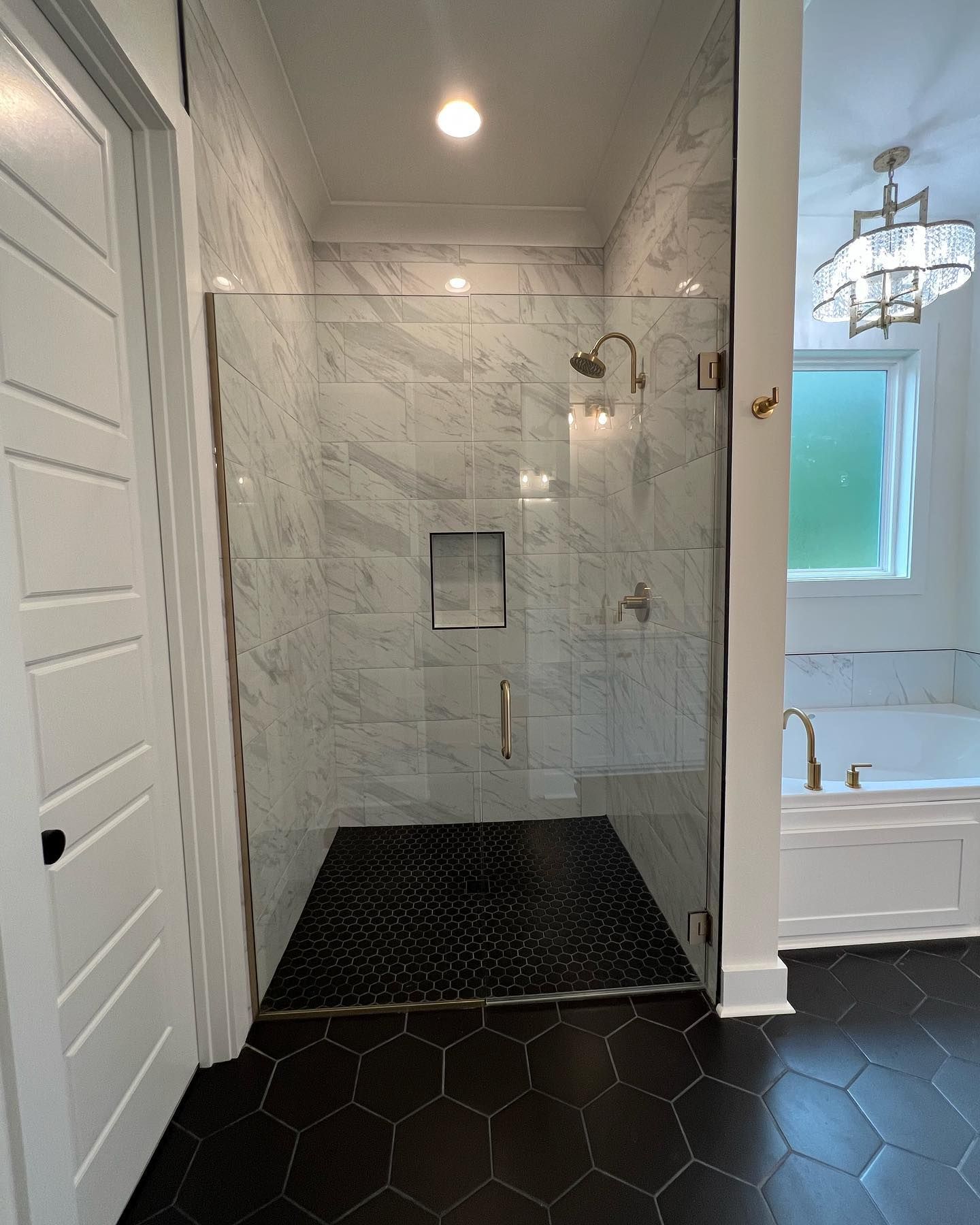 A bathroom with a walk in shower with a glass door