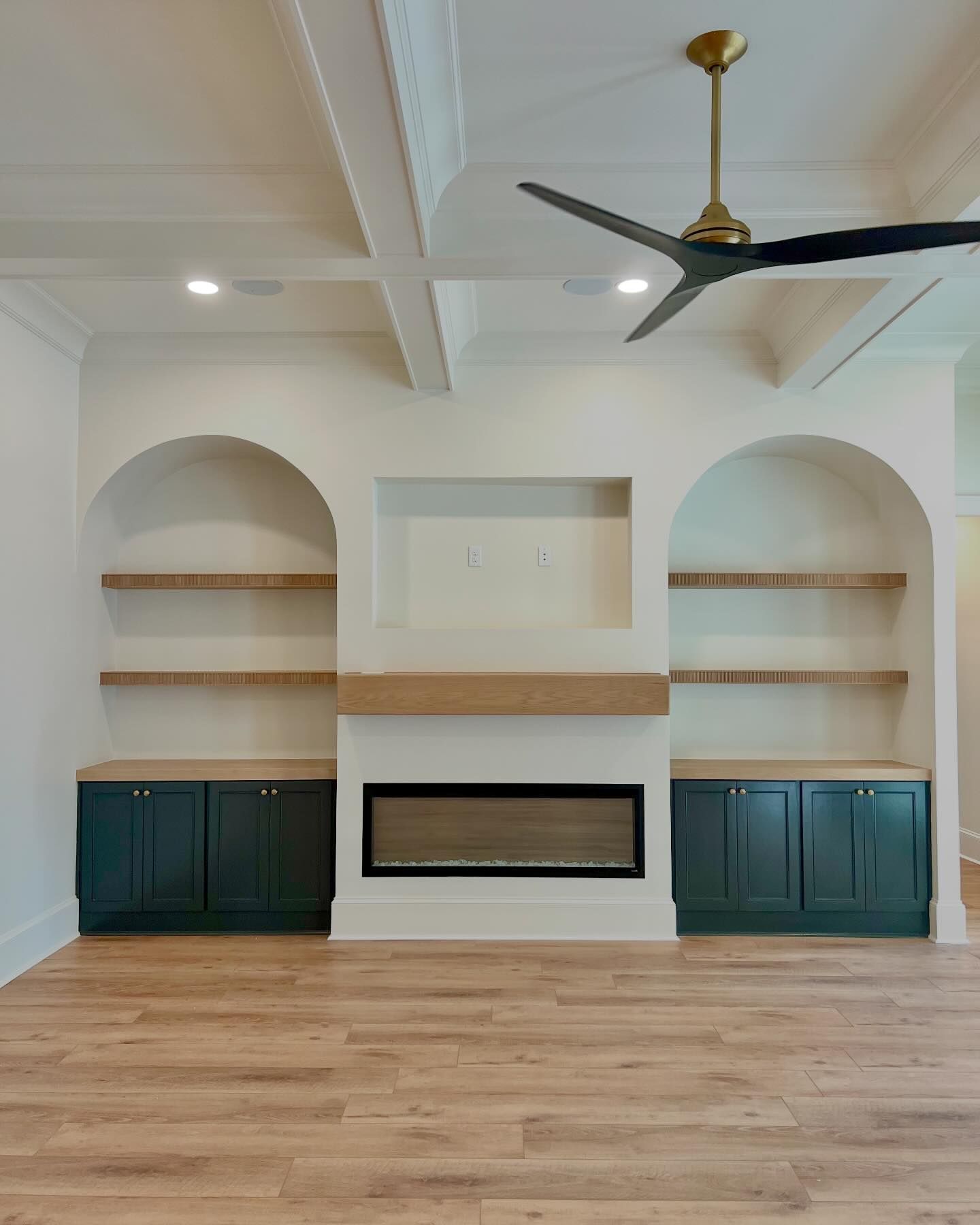 A living room with a fireplace , shelves , and a ceiling fan.