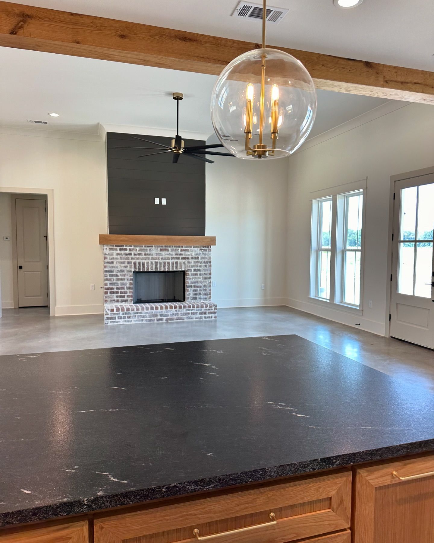 A kitchen with a black counter top and a fireplace in the background.