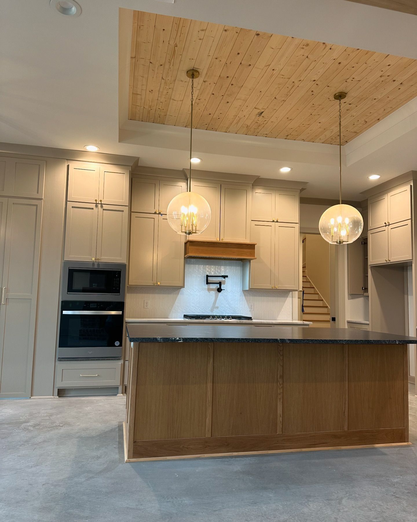 A kitchen with white cabinets and a wooden ceiling