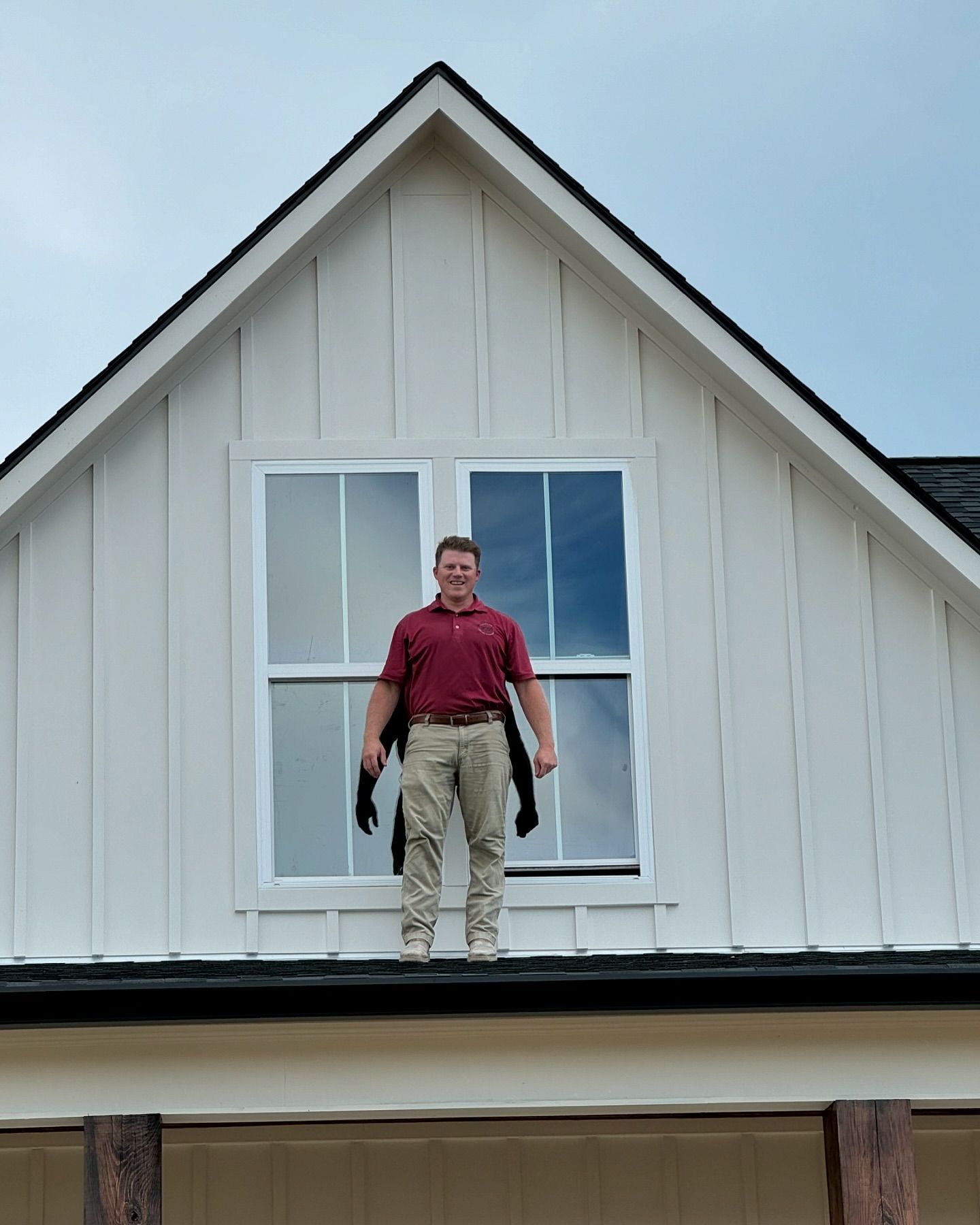 A man is standing on the roof of a white house.