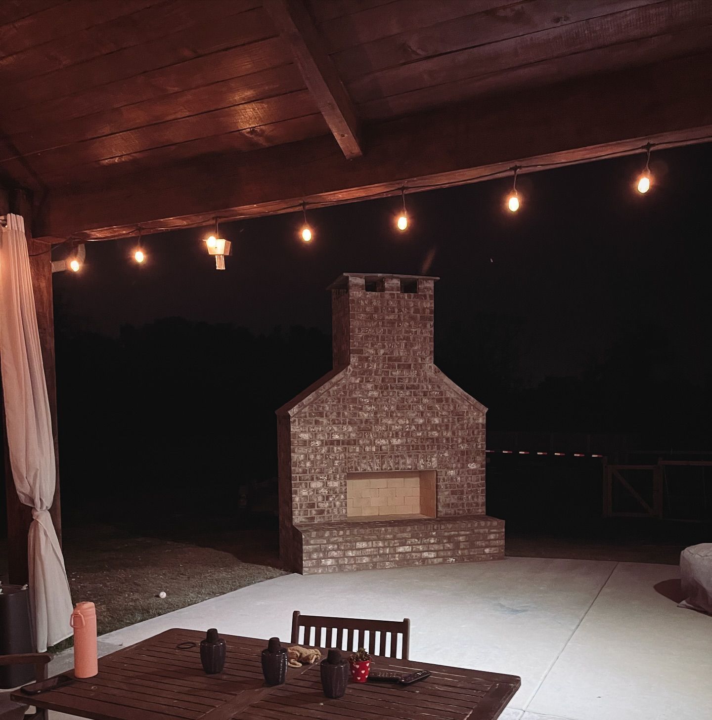 A patio with a fireplace and a table at night