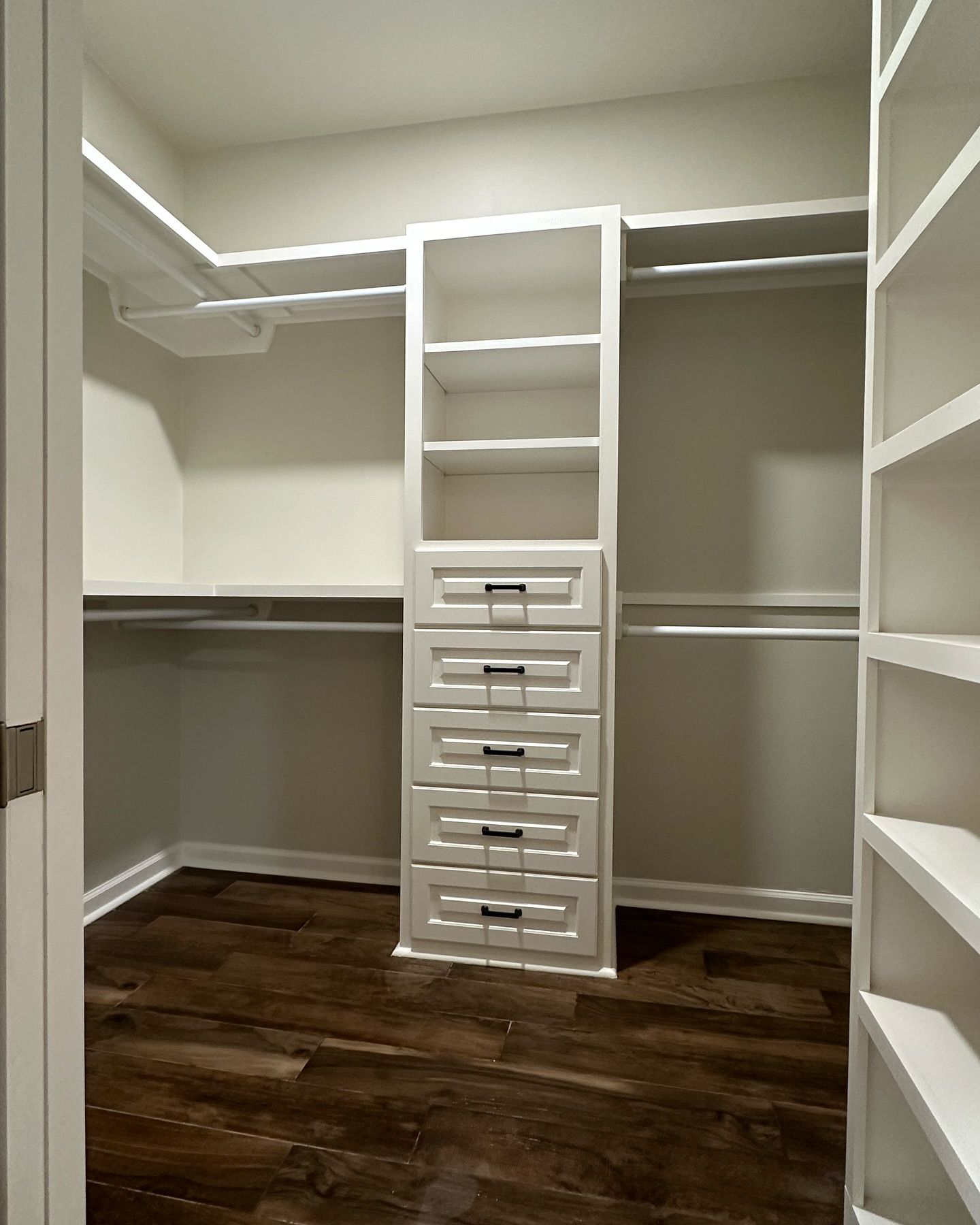 A walk in closet with lots of shelves and drawers.