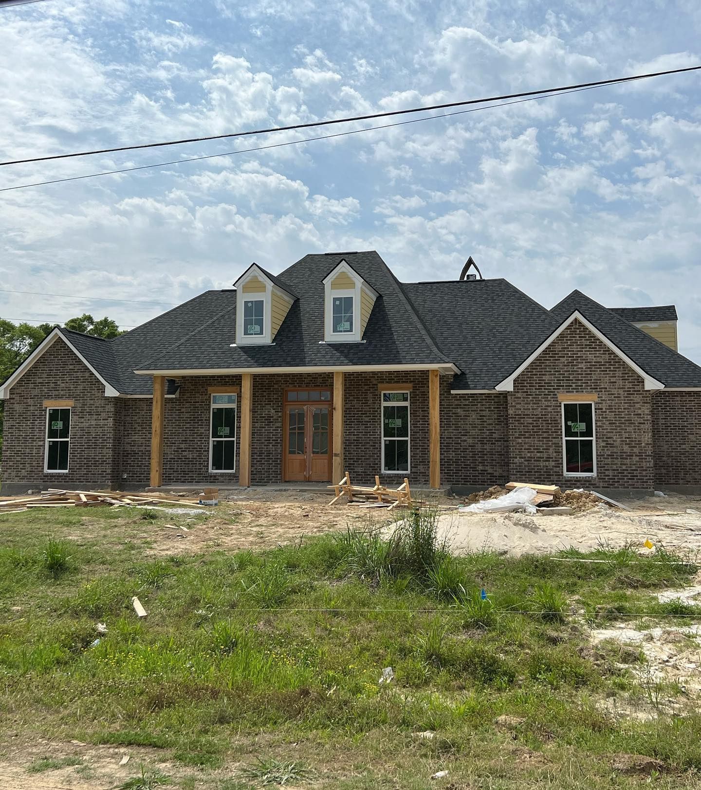 A large brick house is being built in a grassy field.