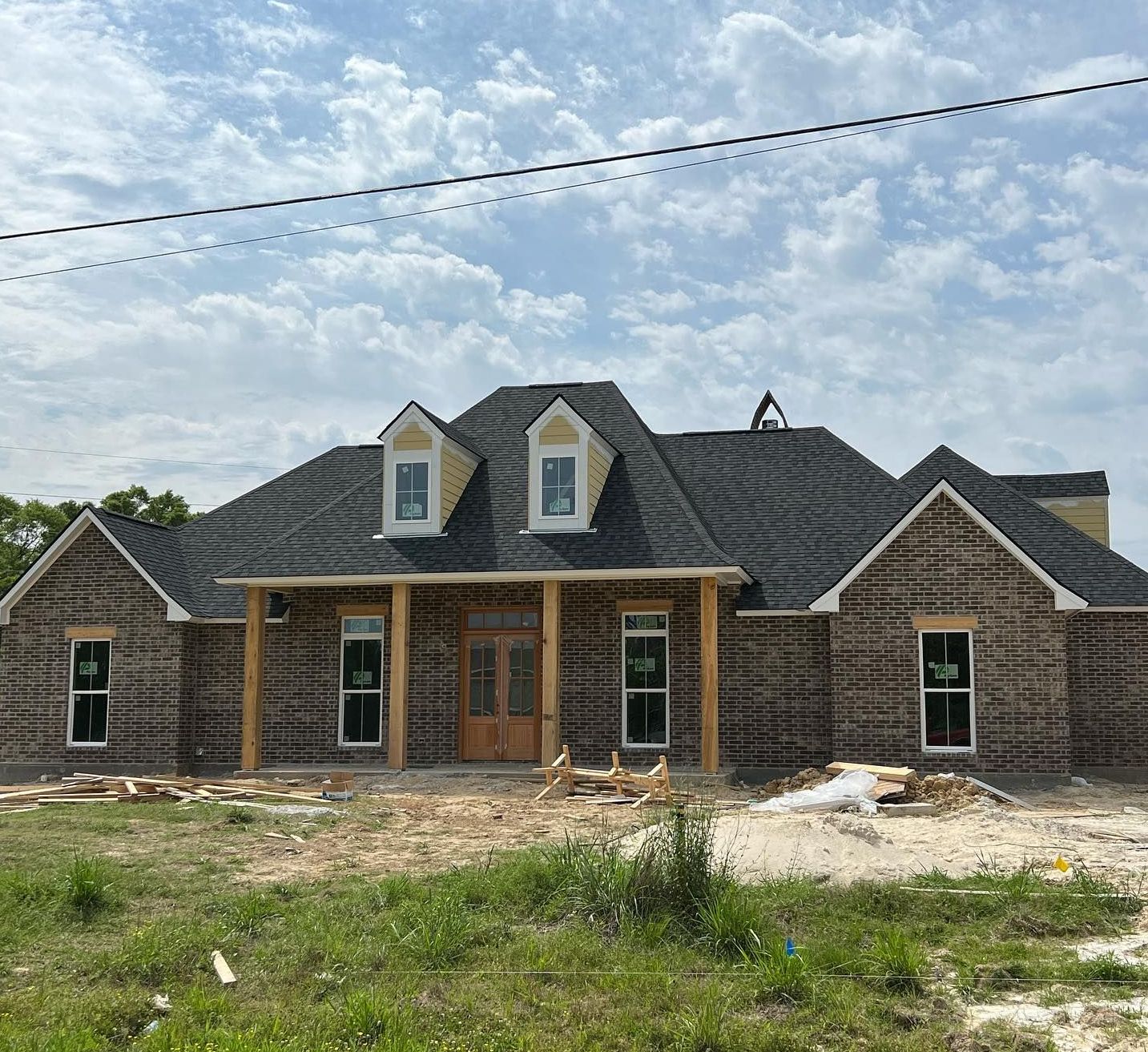 A large brick house with a black roof is being built