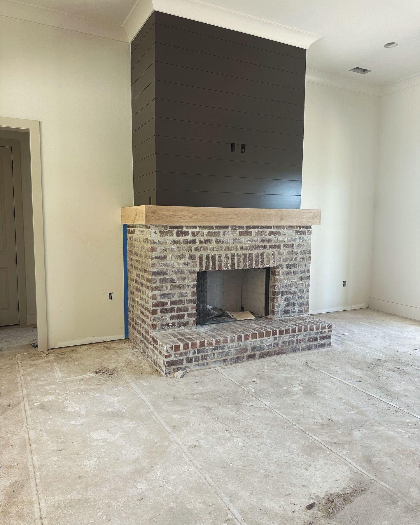 A brick fireplace in an empty room with white walls