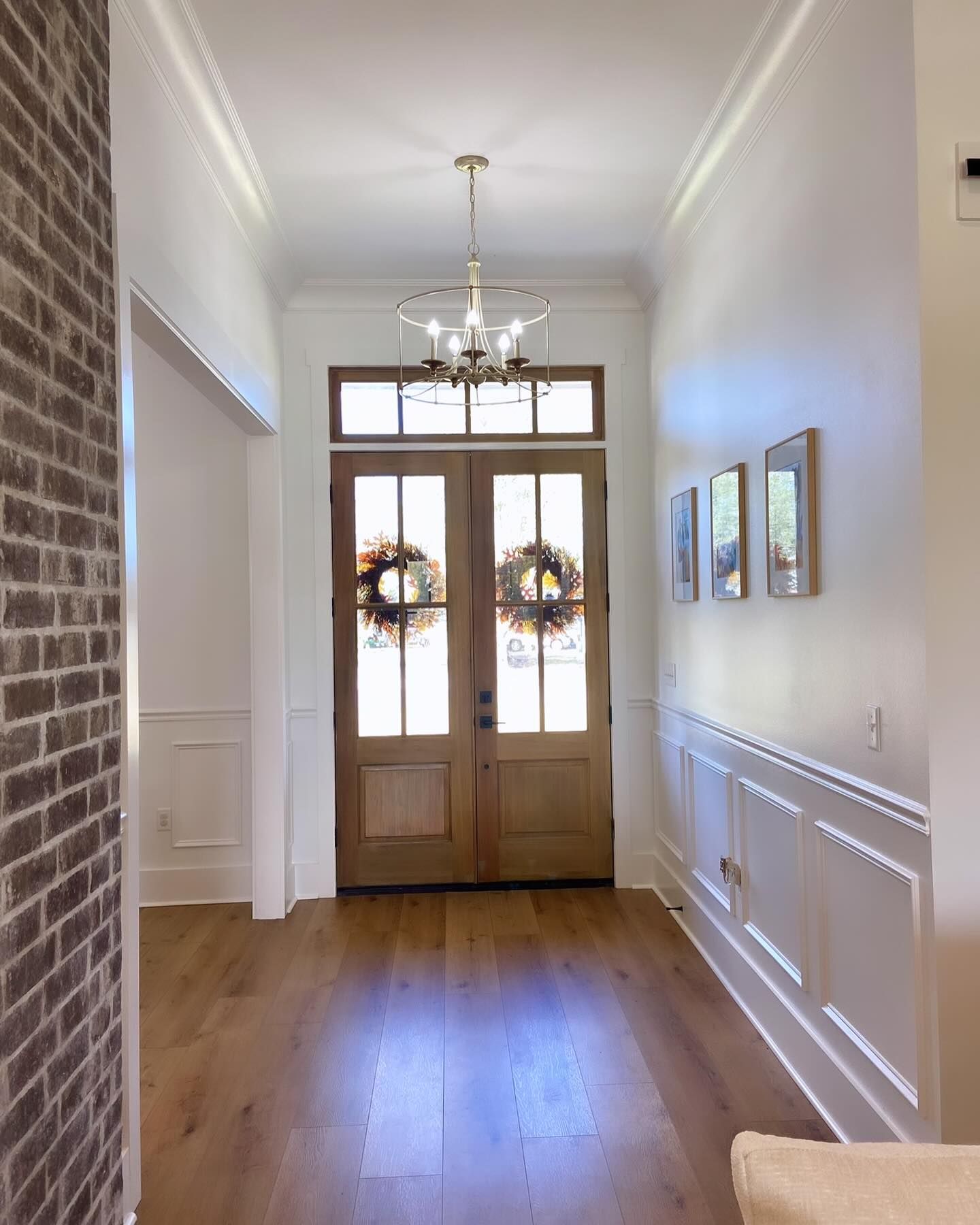 A hallway with a wooden door and a chandelier hanging from the ceiling.